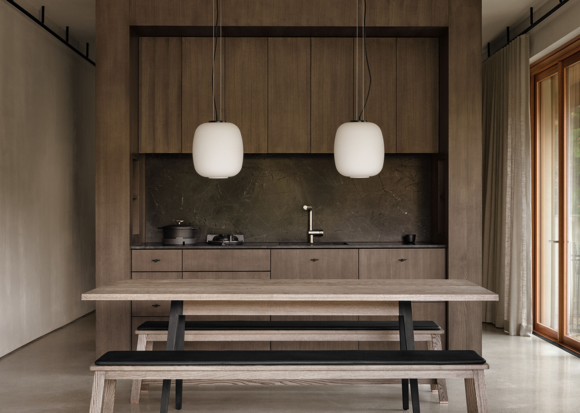 Timber kitchenette wall with stone counter and twin pendant lights above bench seating