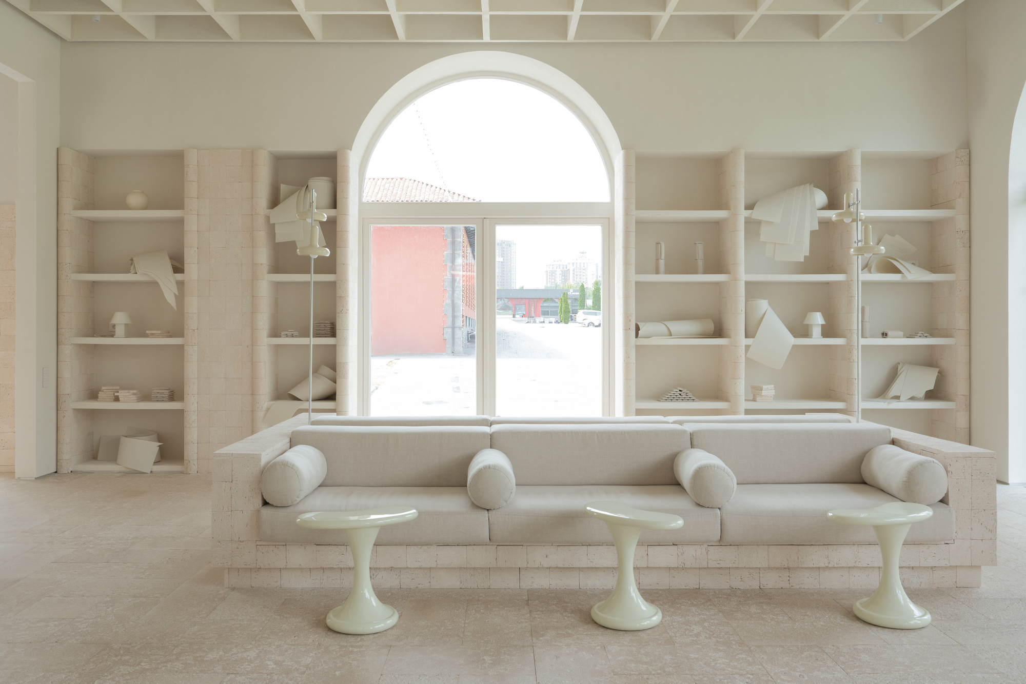 Built-in seating bench beneath arched window with shelving displaying ceramics and models