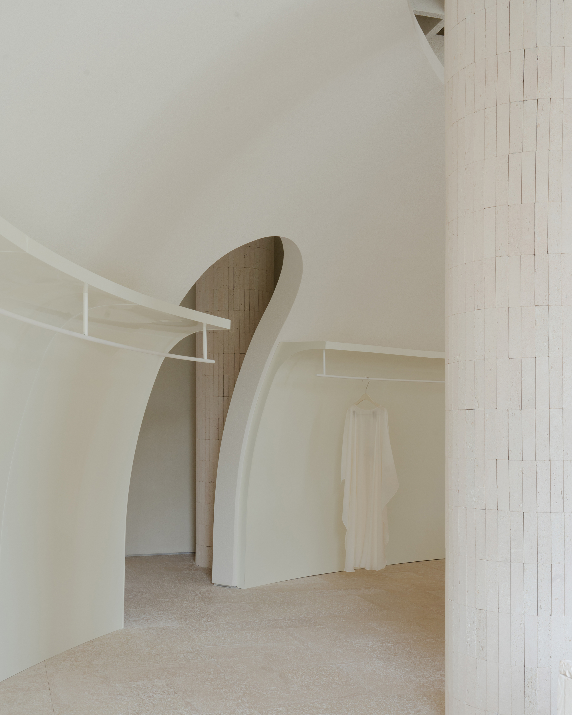 Arched opening revealing a sculptural staircase clad in vertical brick tile