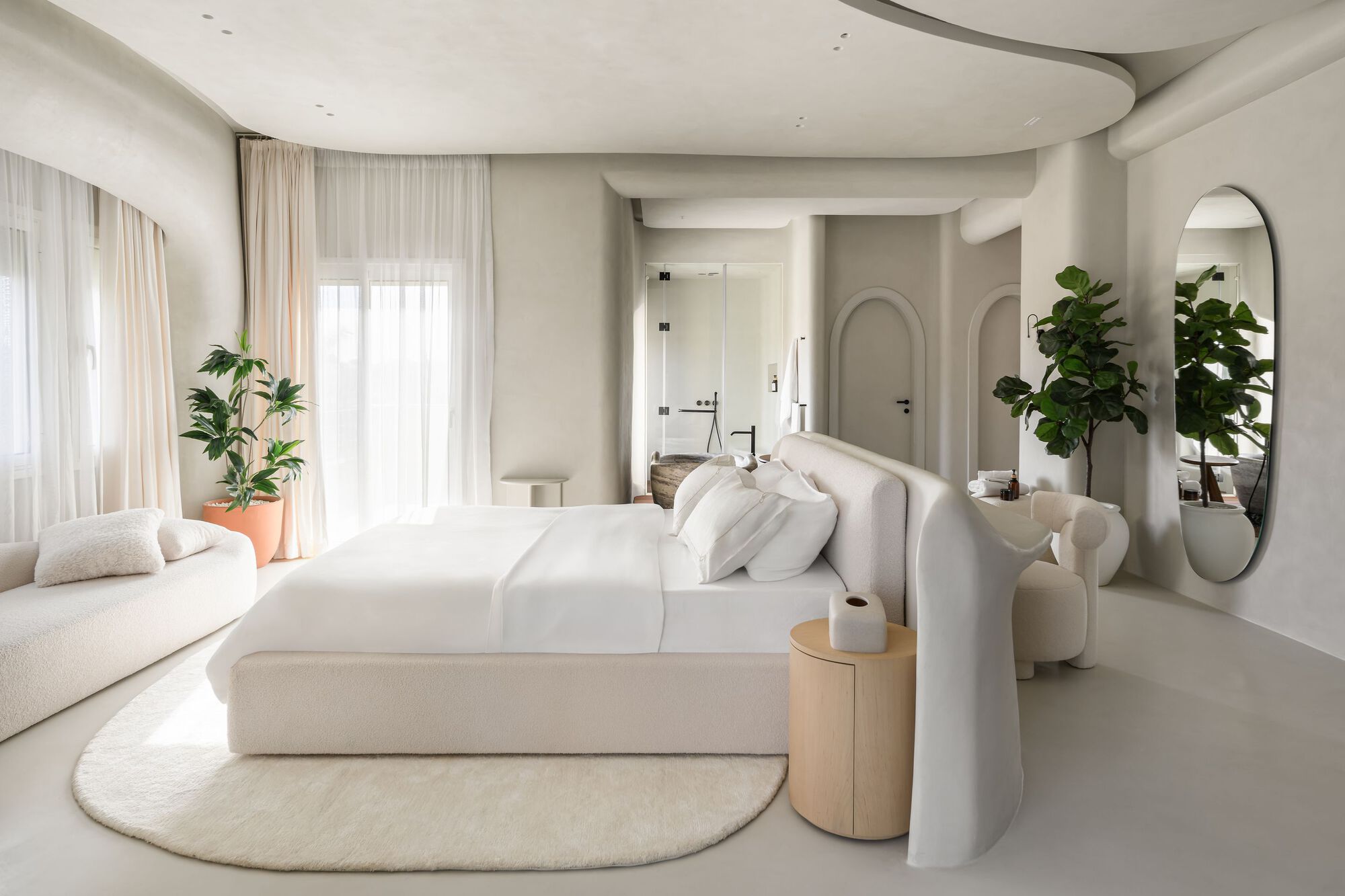 Open bedroom suite with curved ceiling, arched doorways and indoor plants flanking upholstered seating
