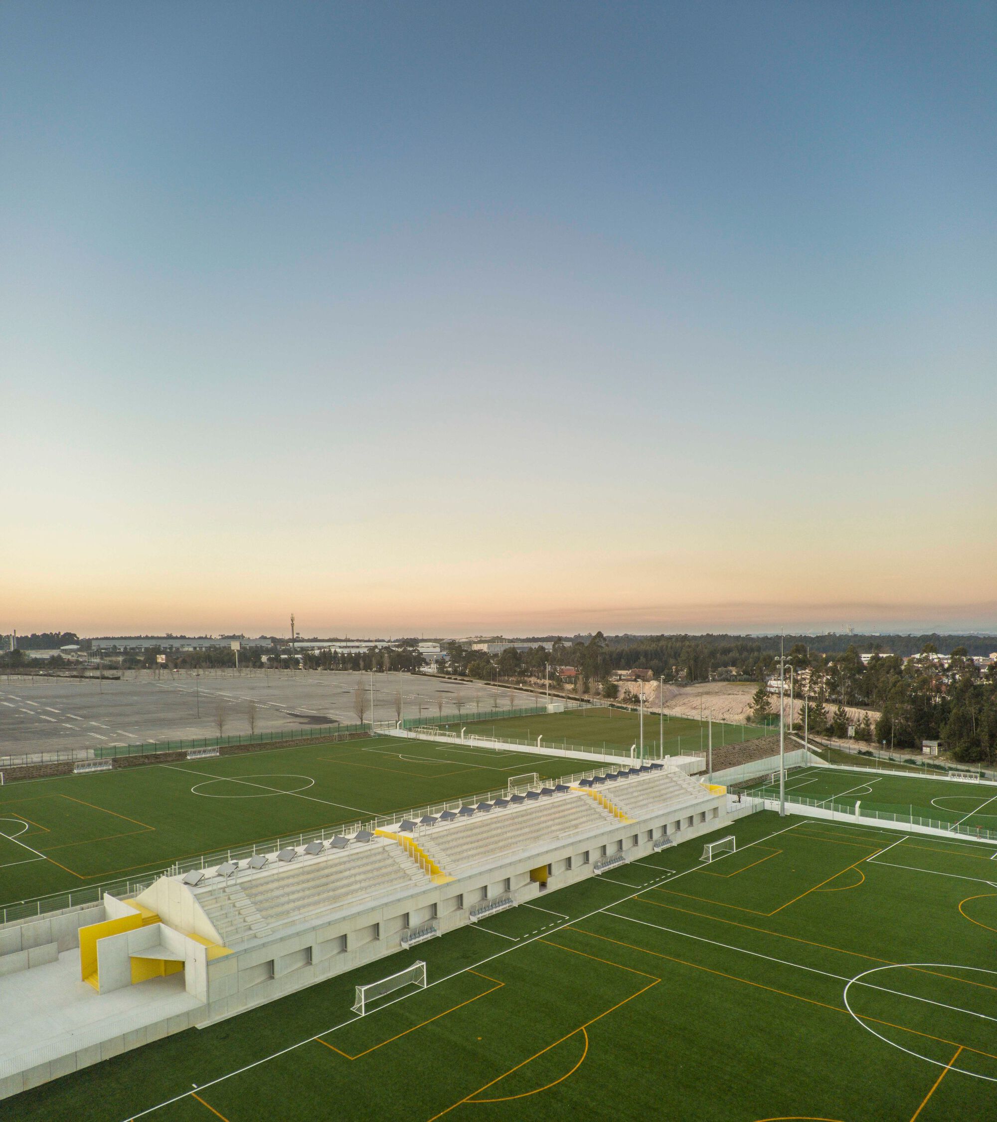 Elevated view of the canopy structure and tiered seating overlooking multiple sports fields at dusk