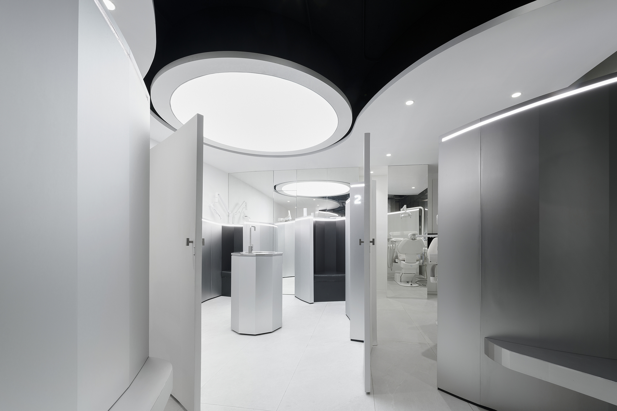 White interior with curved ceiling coffers and cylindrical display podiums beneath circular light fixtures