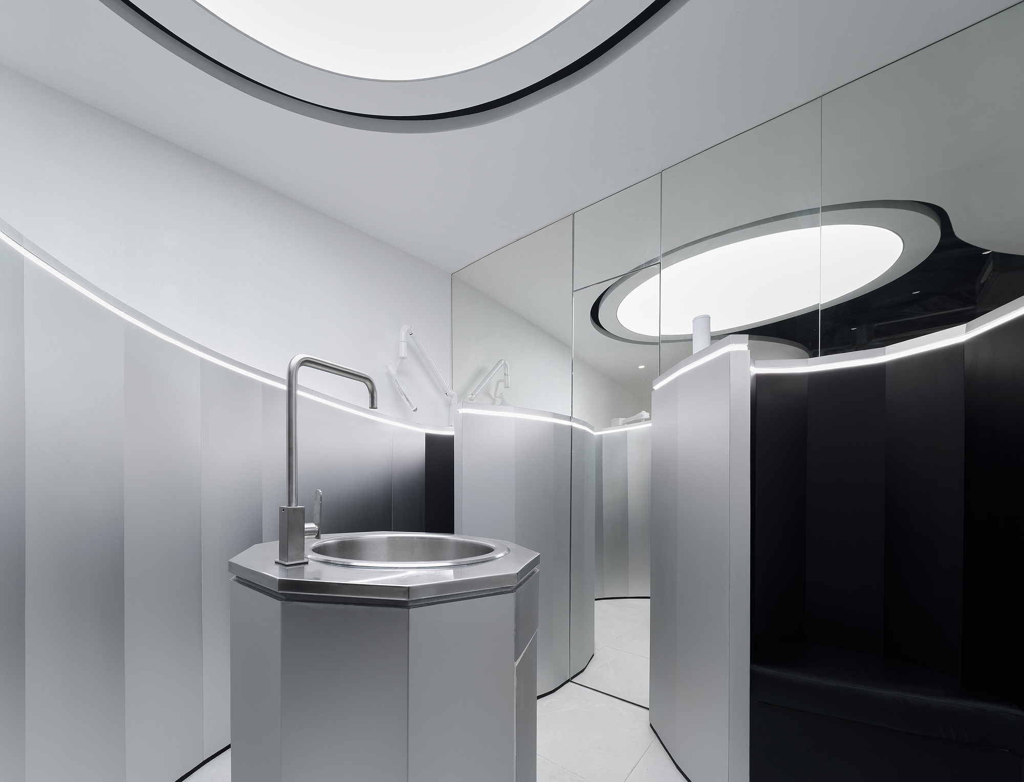 Octagonal sink with brushed metal basin and faucet beneath a curved black and white ceiling element