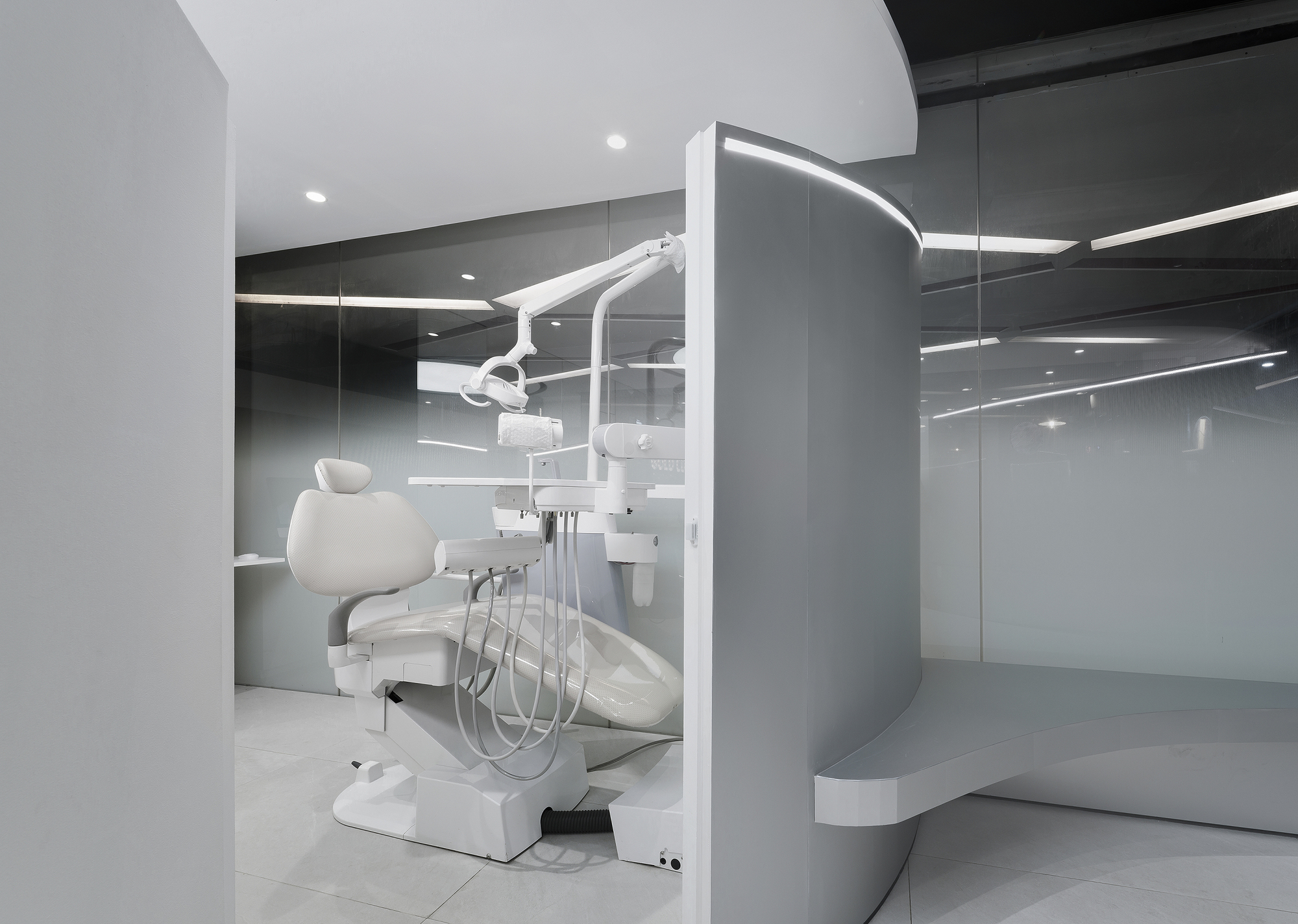Dental treatment station with chair and articulating light within a curved partition and mirrored wall