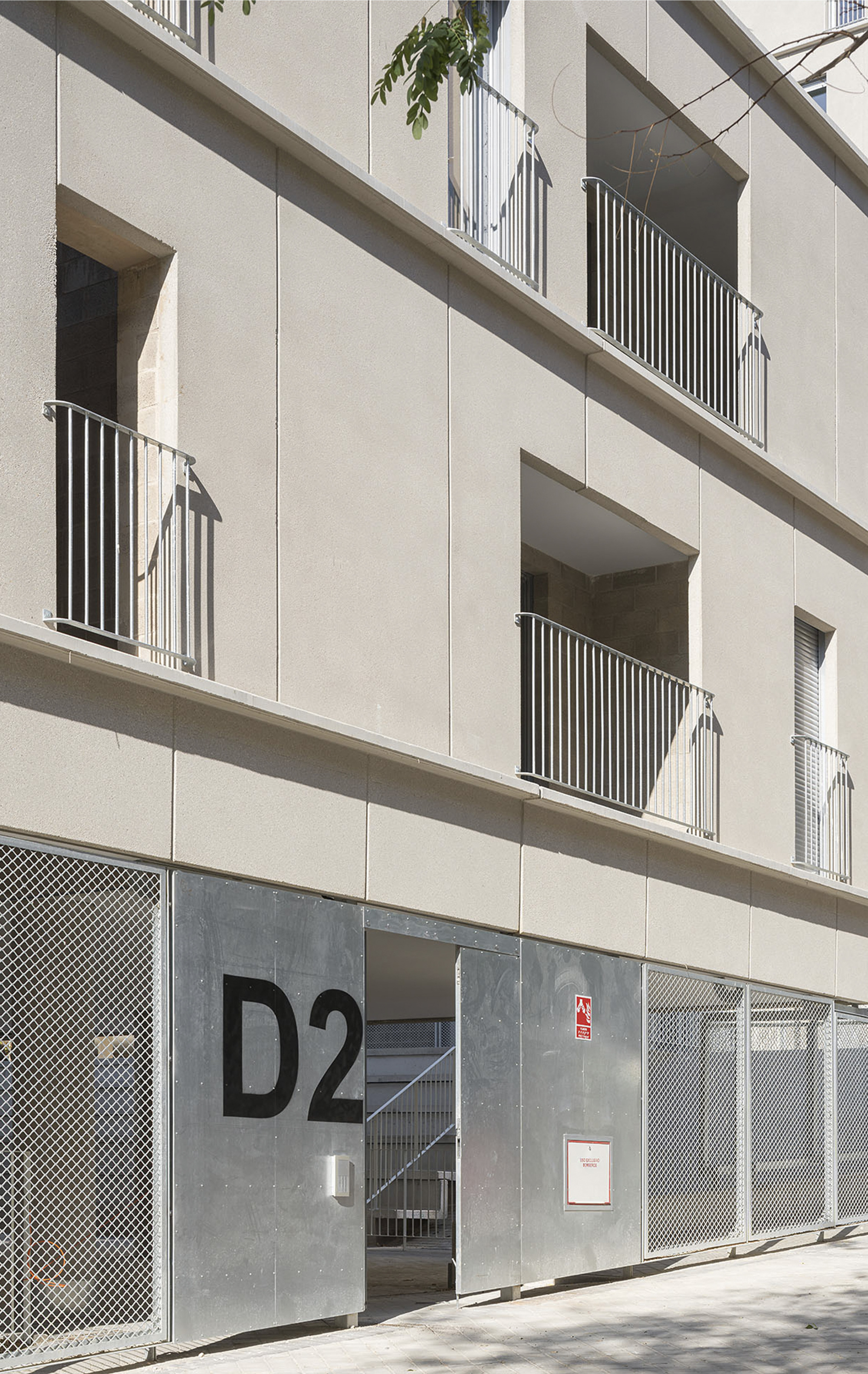 Ground-floor entrance with perforated metal screens and a metal door marked with building signage