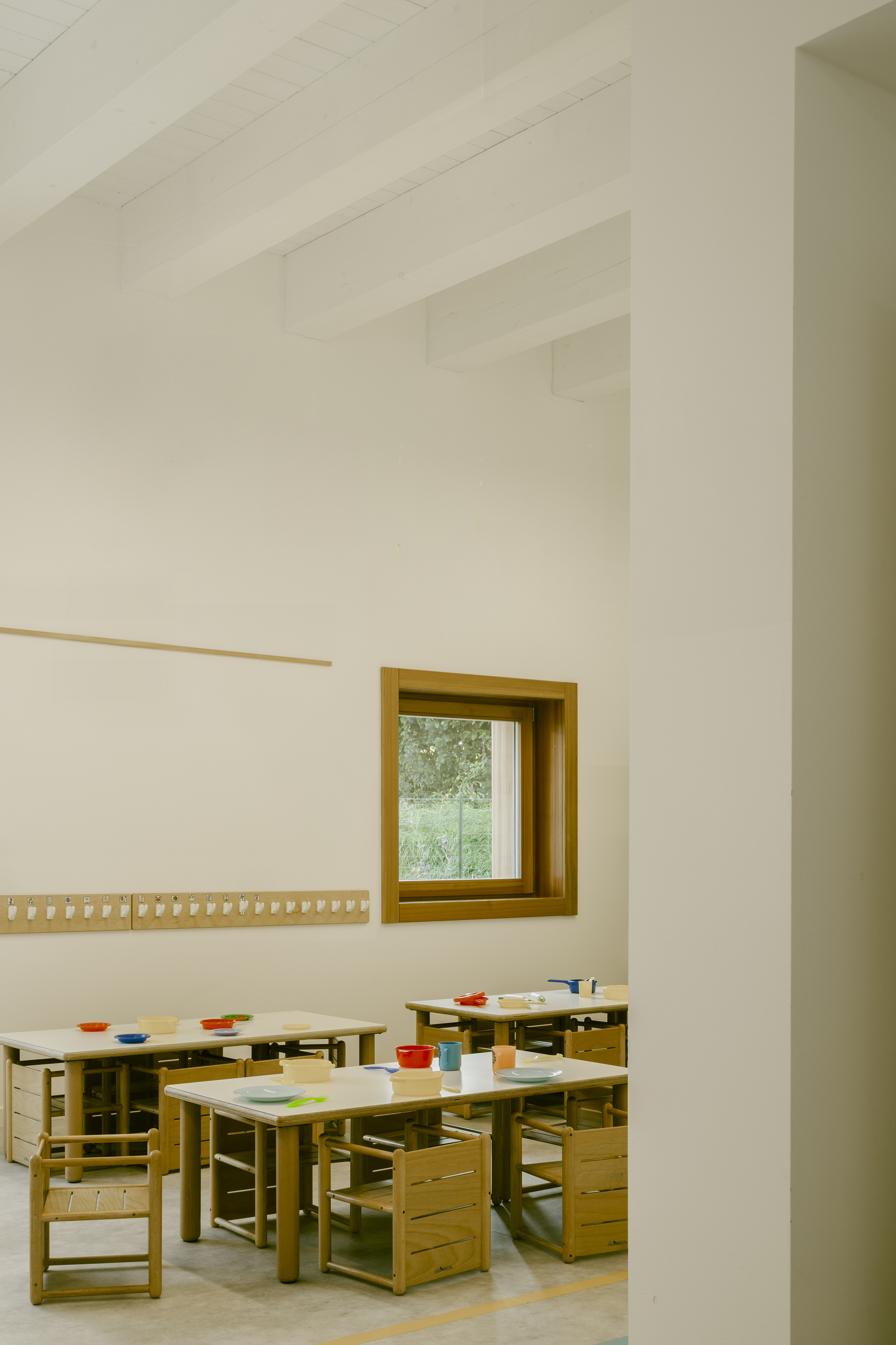 Classroom interior with timber furniture and exposed beam ceiling framed through a doorway
