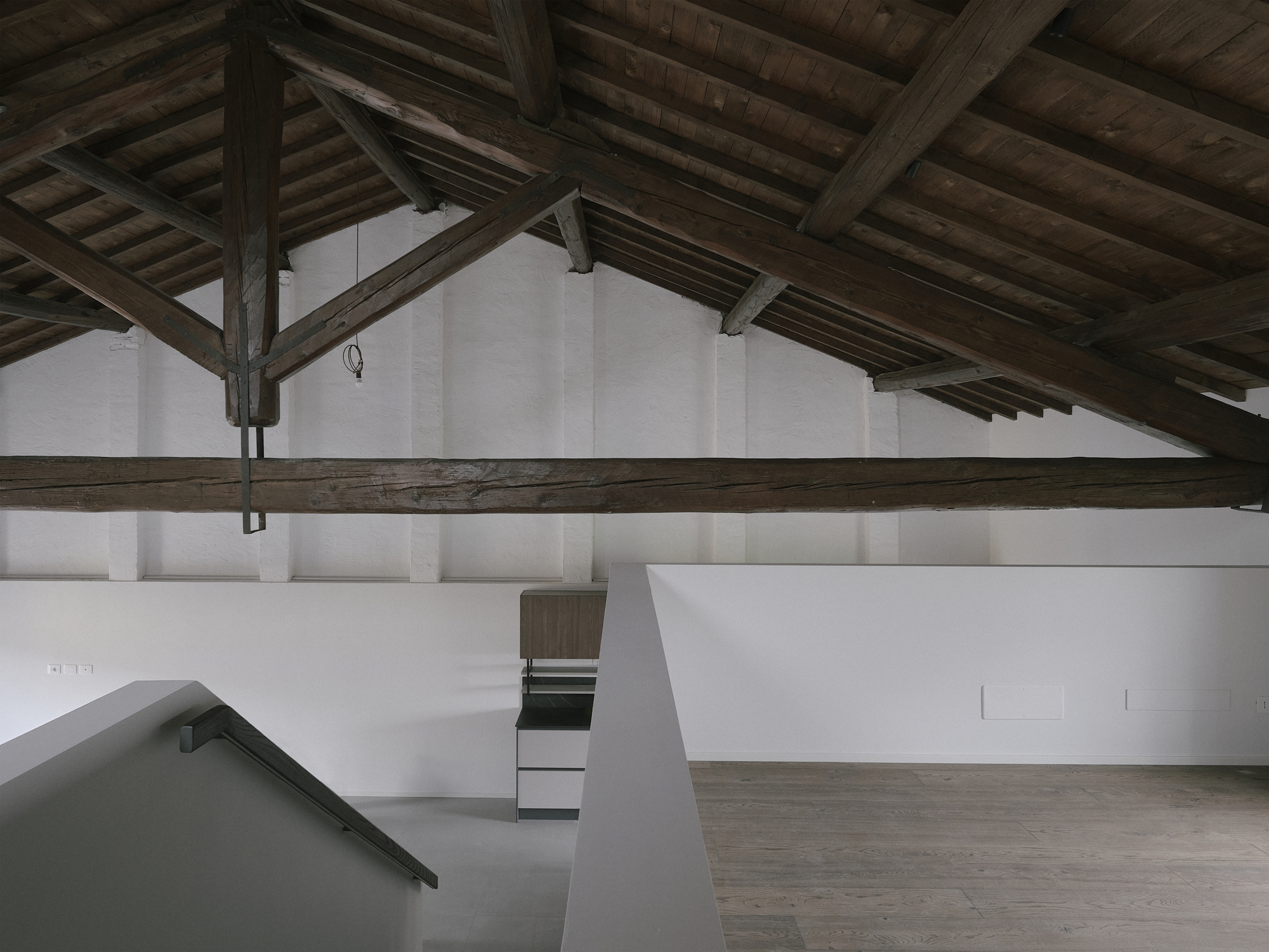 Upper level gallery with white walls and exposed timber beams and columns overhead