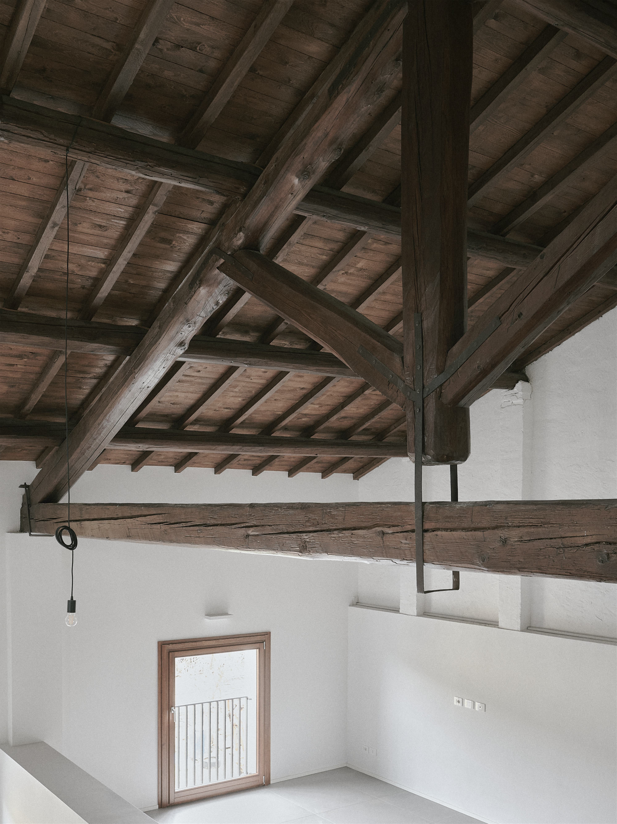 Mezzanine level with exposed timber roof structure and metal railing overlooking a lower room