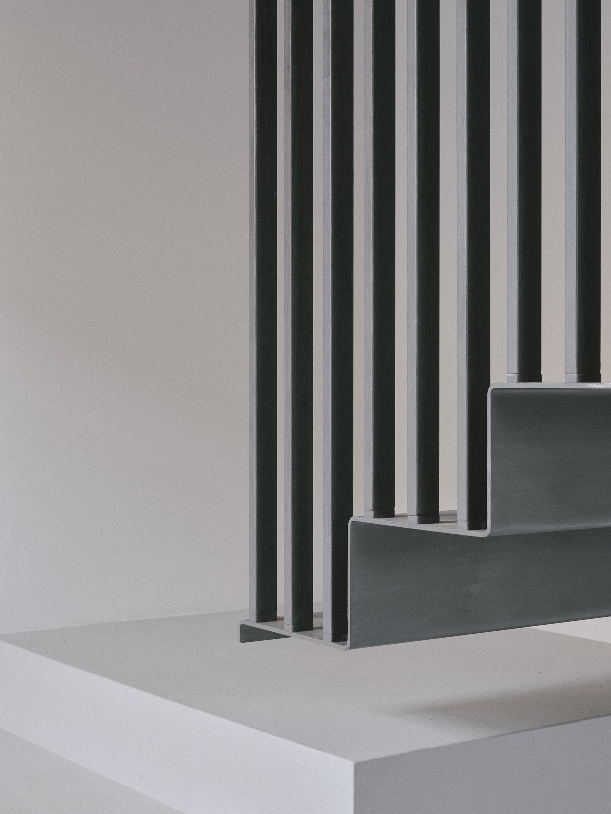 Detail of grey stairs with vertical metal rods passing through the treads and landing
