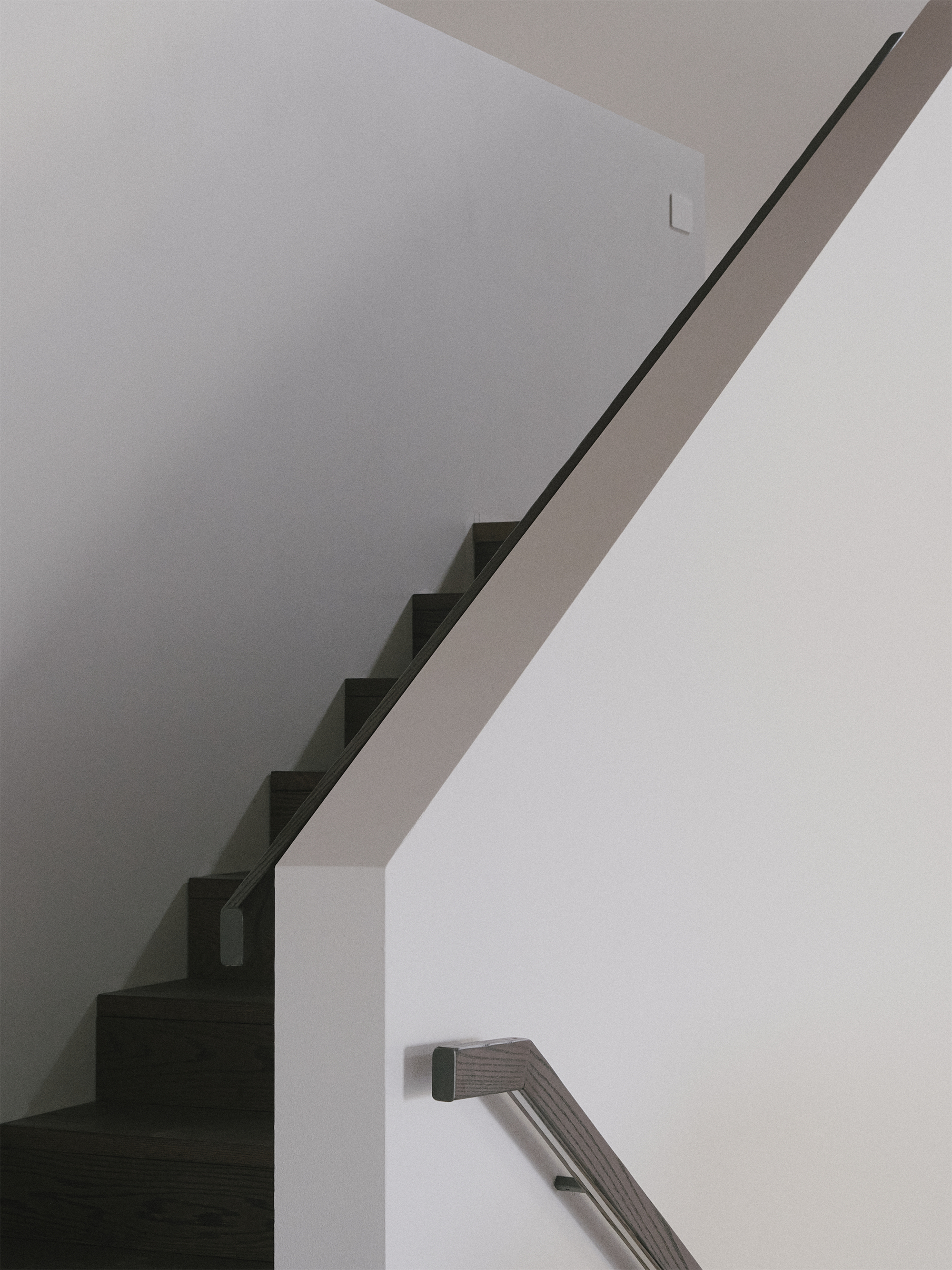Interior view of cantilevered staircase with thin metal handrail ascending along white walls