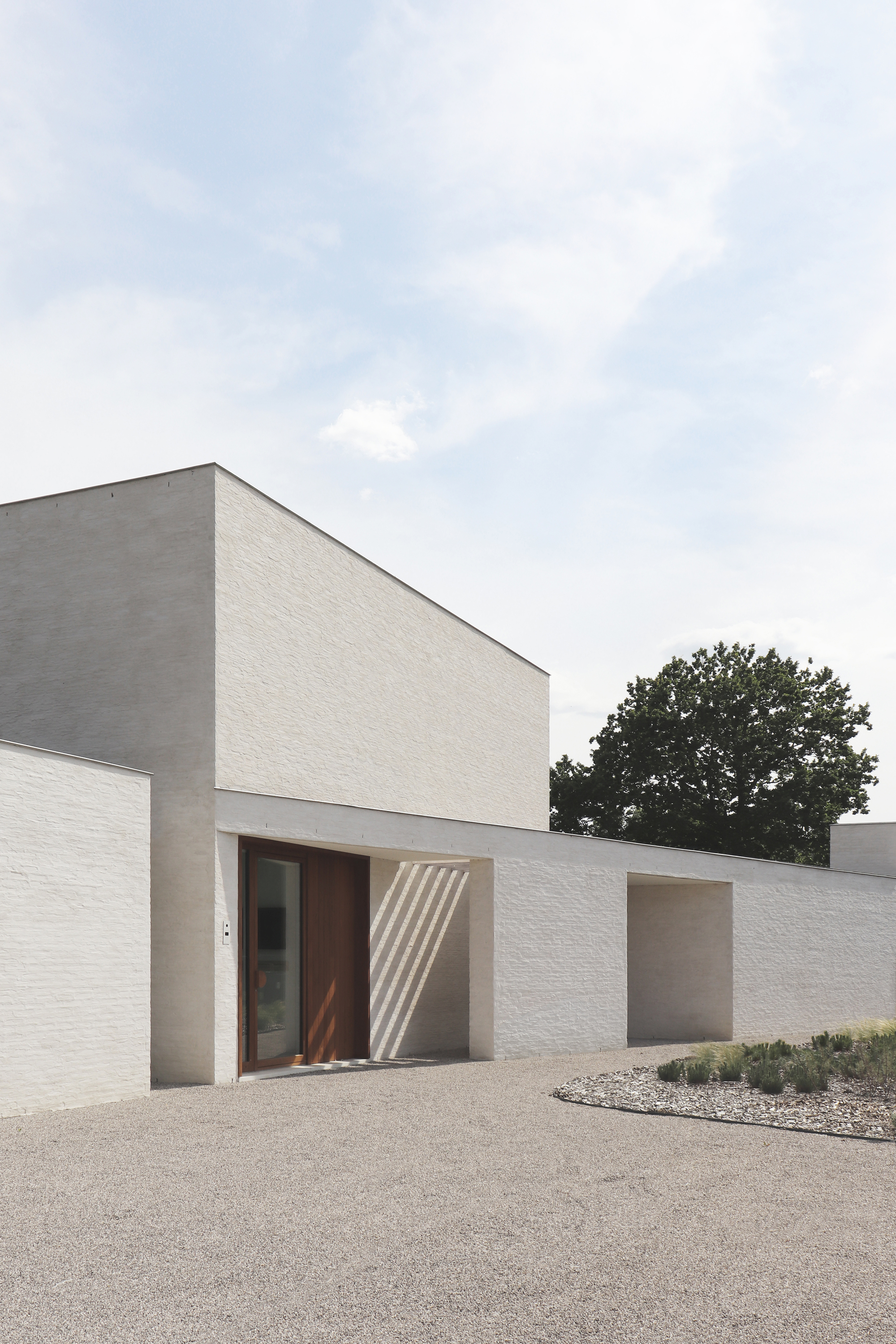 Street-facing elevation showing timber entry door set in white and grey brick walls