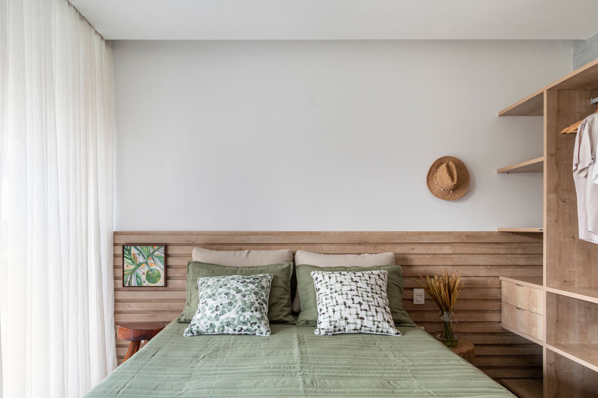 Bedroom with horizontal timber headboard wall and white curtains filtering daylight