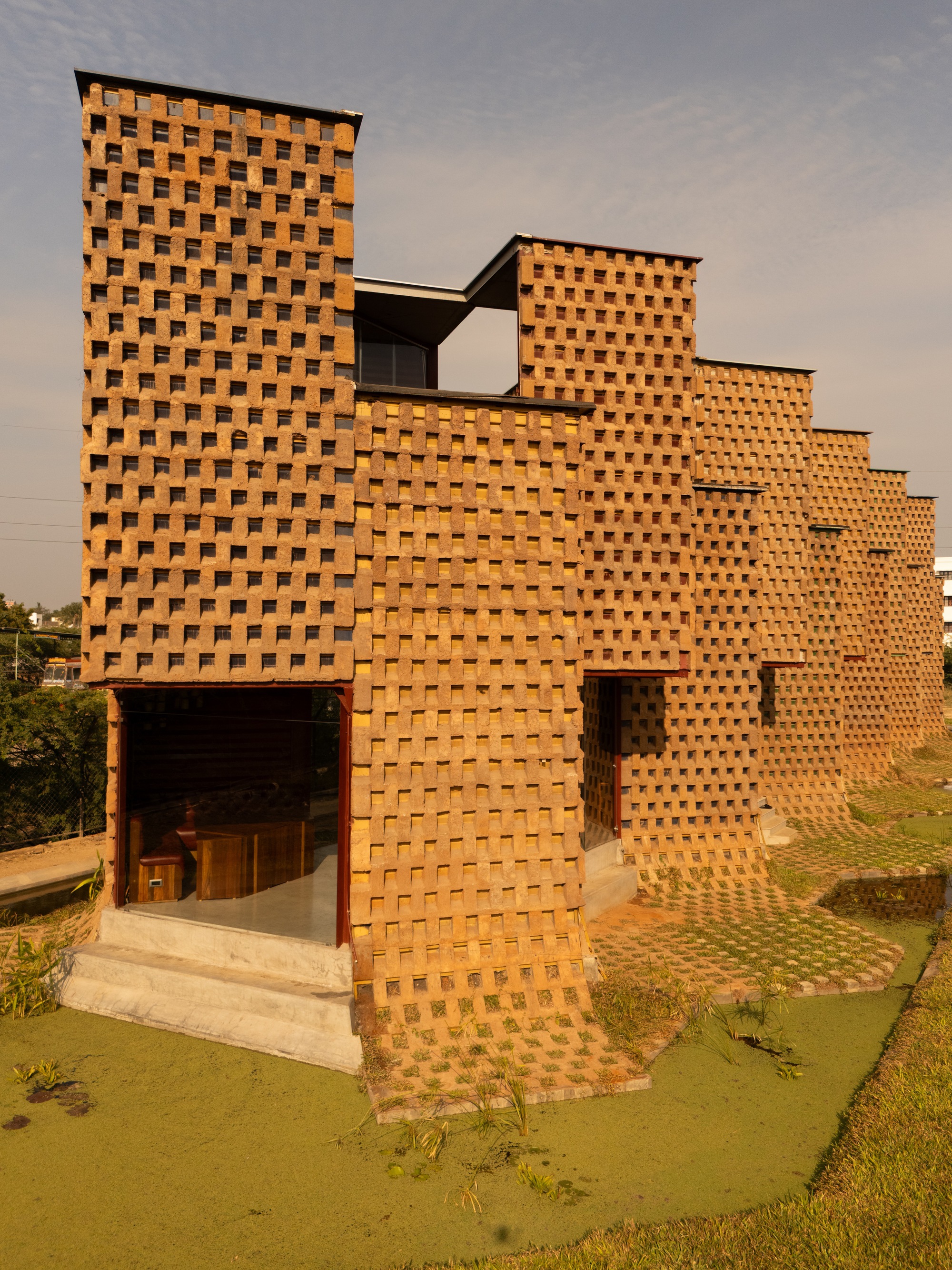 Corner view of the stepped brick volume rising from a grass slope in warm afternoon light
