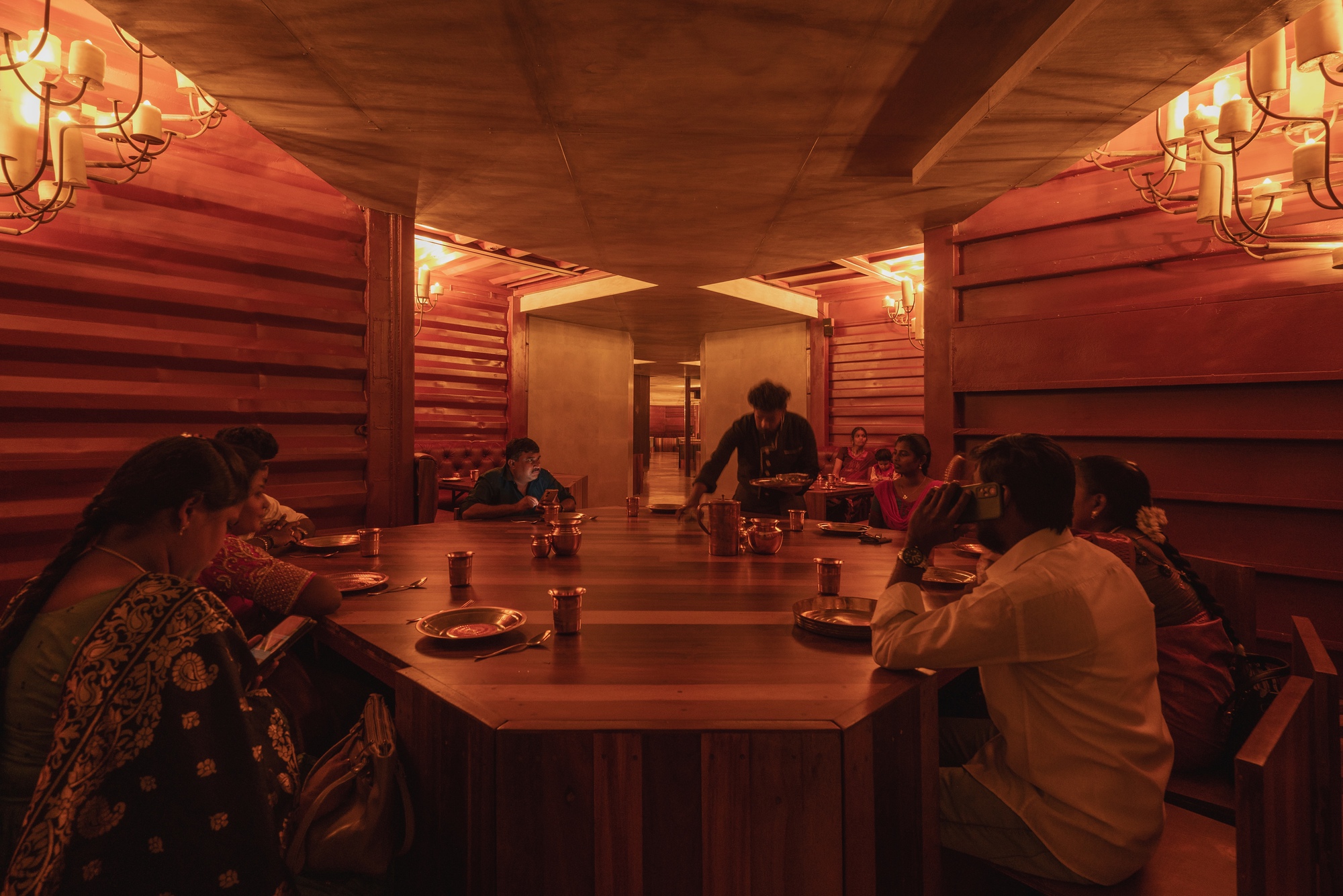 Dining space with communal timber table and horizontal timber wall cladding under a coffered ceiling