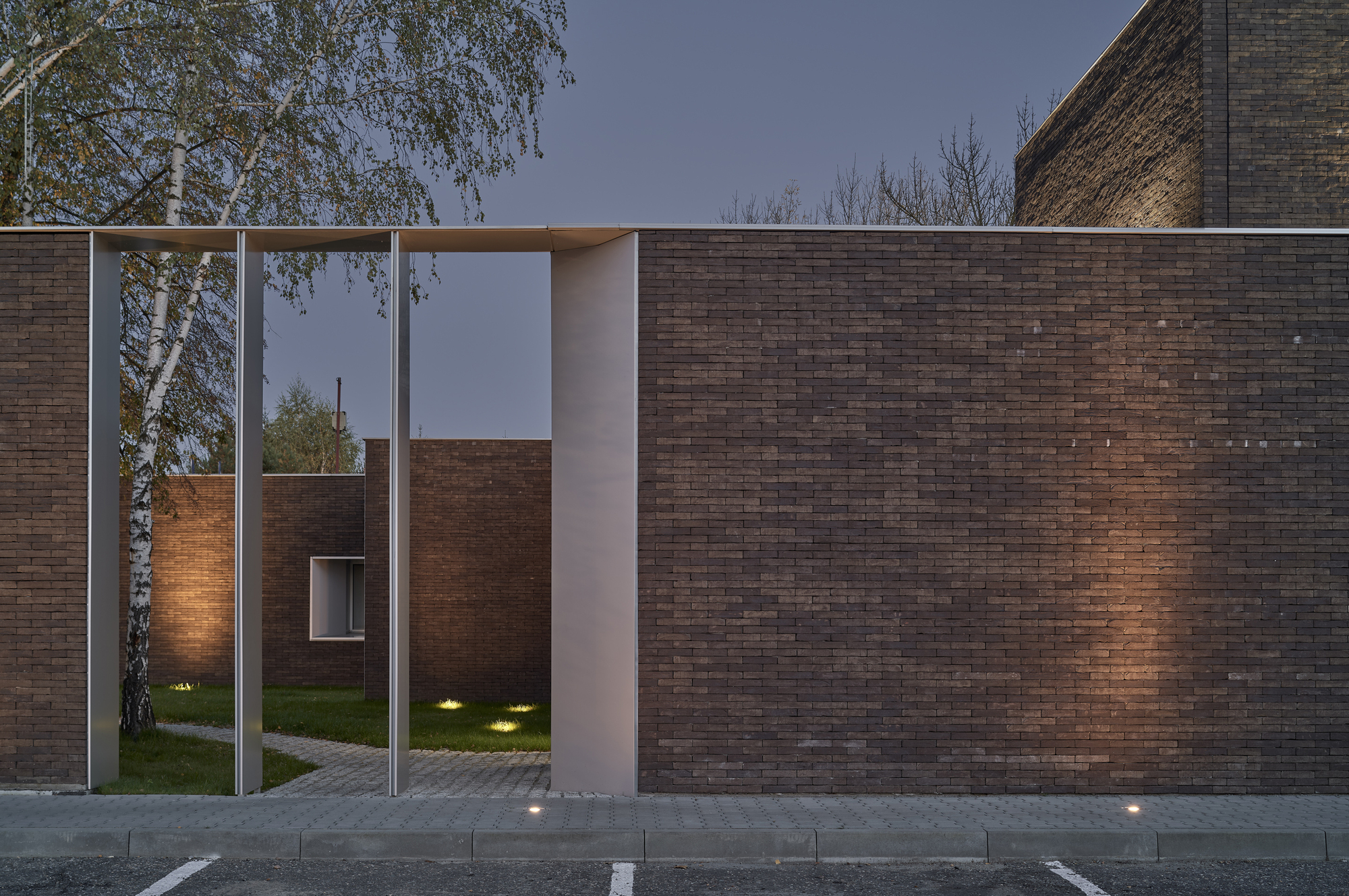 Dark brick wall with a framed entry portal and recessed lighting at twilight