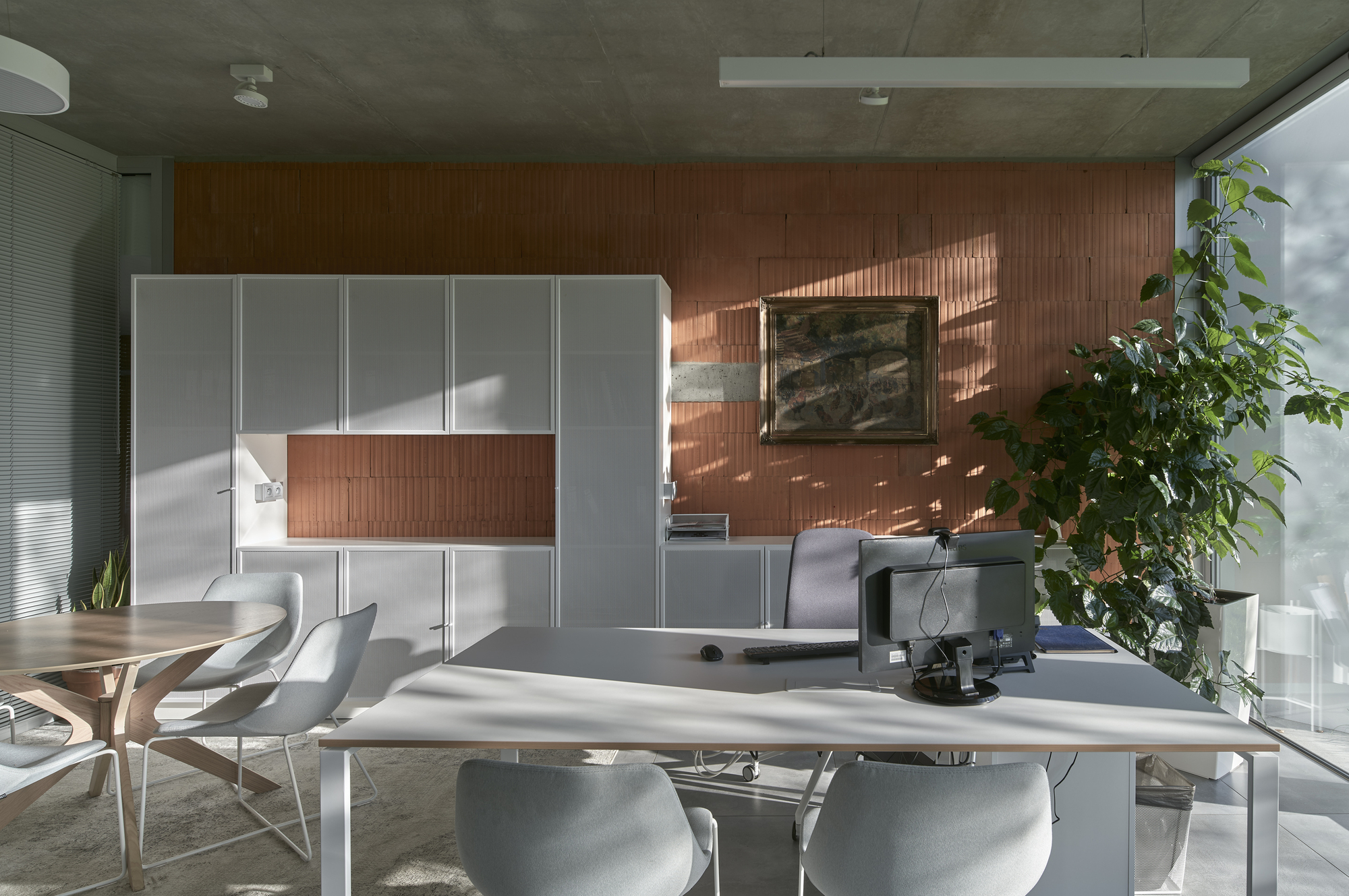 Workspace with white desk and vertical timber slat wall illuminated by afternoon sunlight through corrugated glass