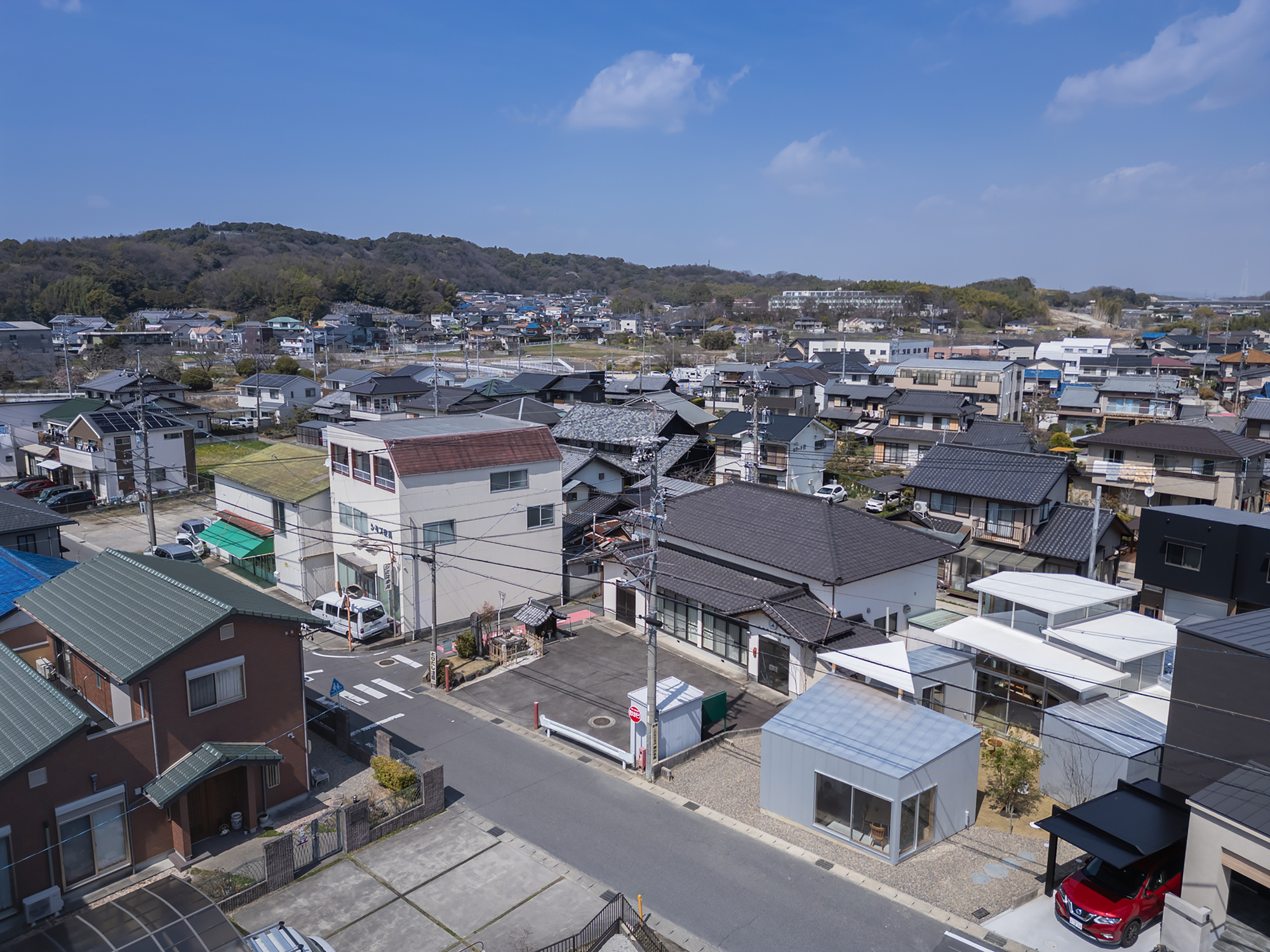 Aerial view of a dense residential neighborhood with varied roof types under blue sky