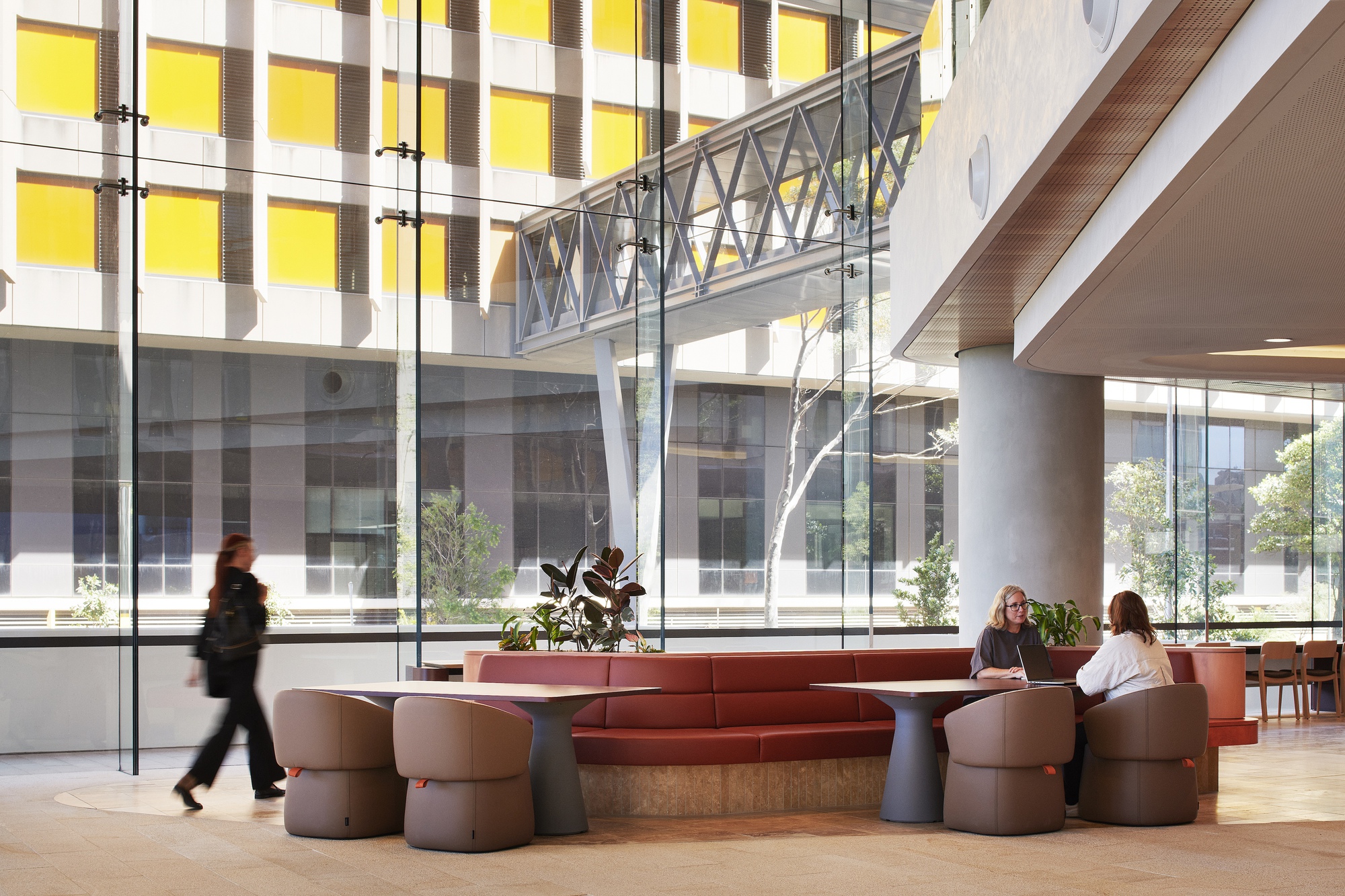 Interior lobby with circular seating pods and a steel bridge spanning overhead