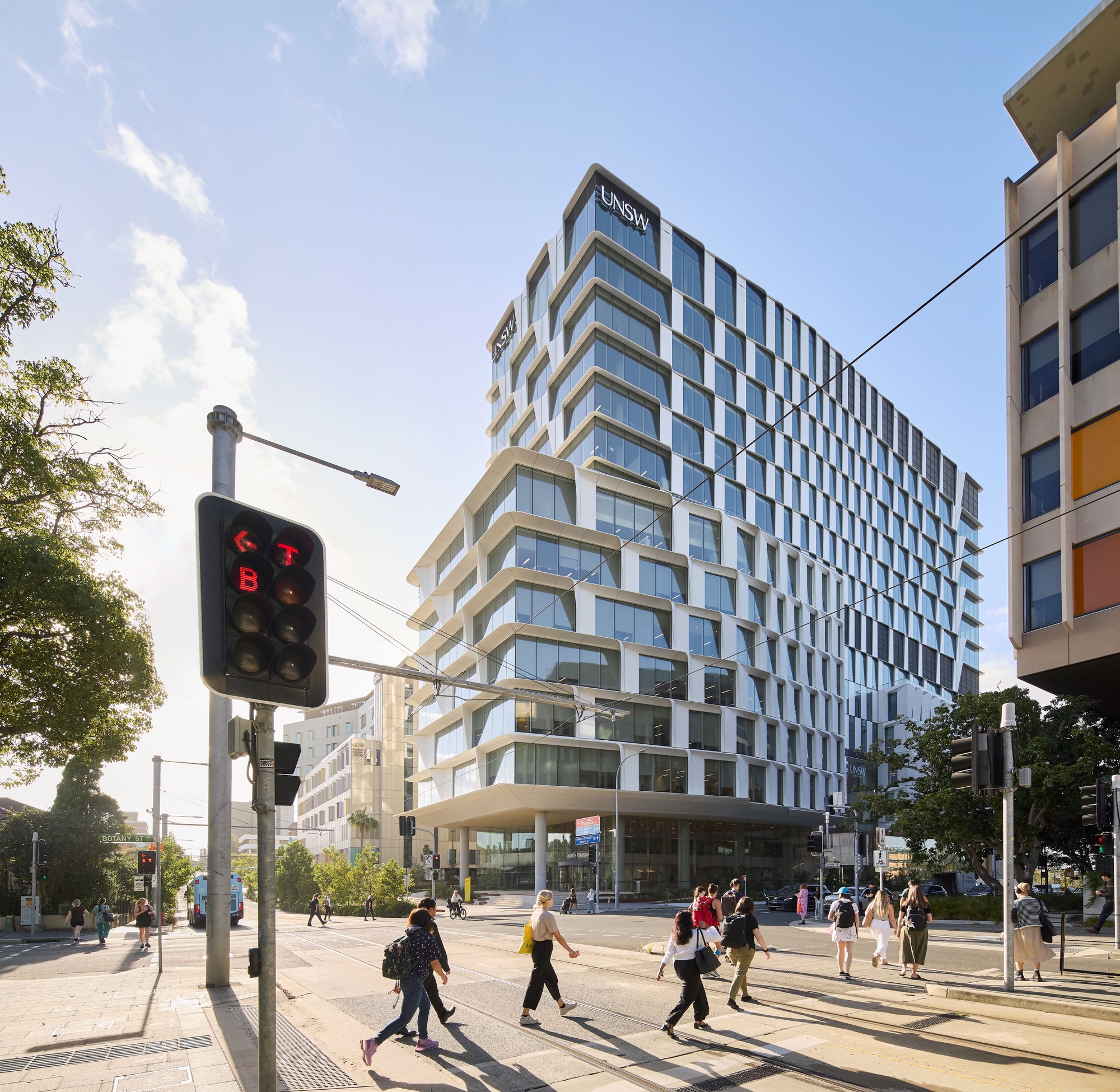 Street corner view of the stepped facade with pedestrians crossing under late afternoon light