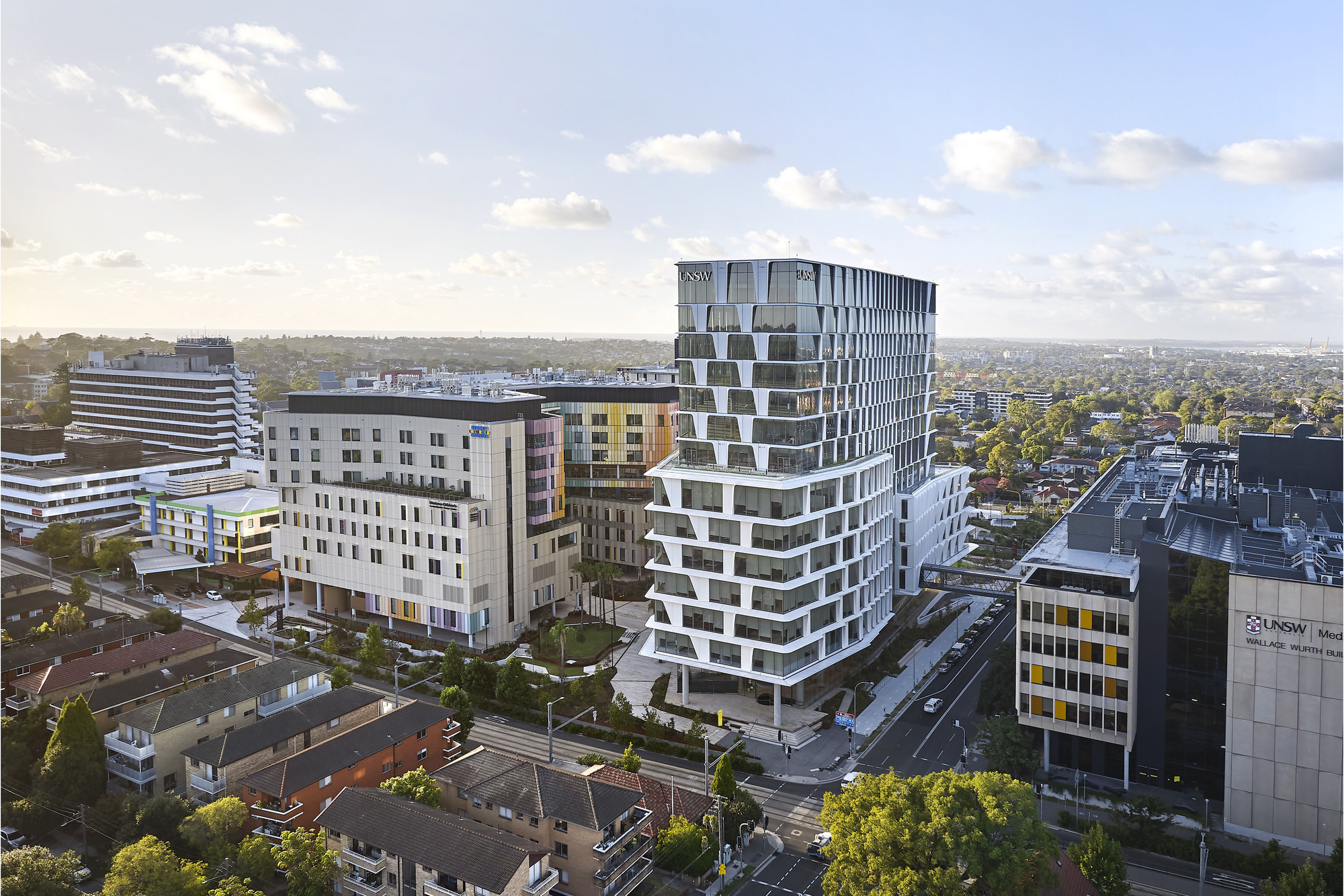 Aerial view of the stacked balcony tower rising above surrounding residential blocks under scattered clouds