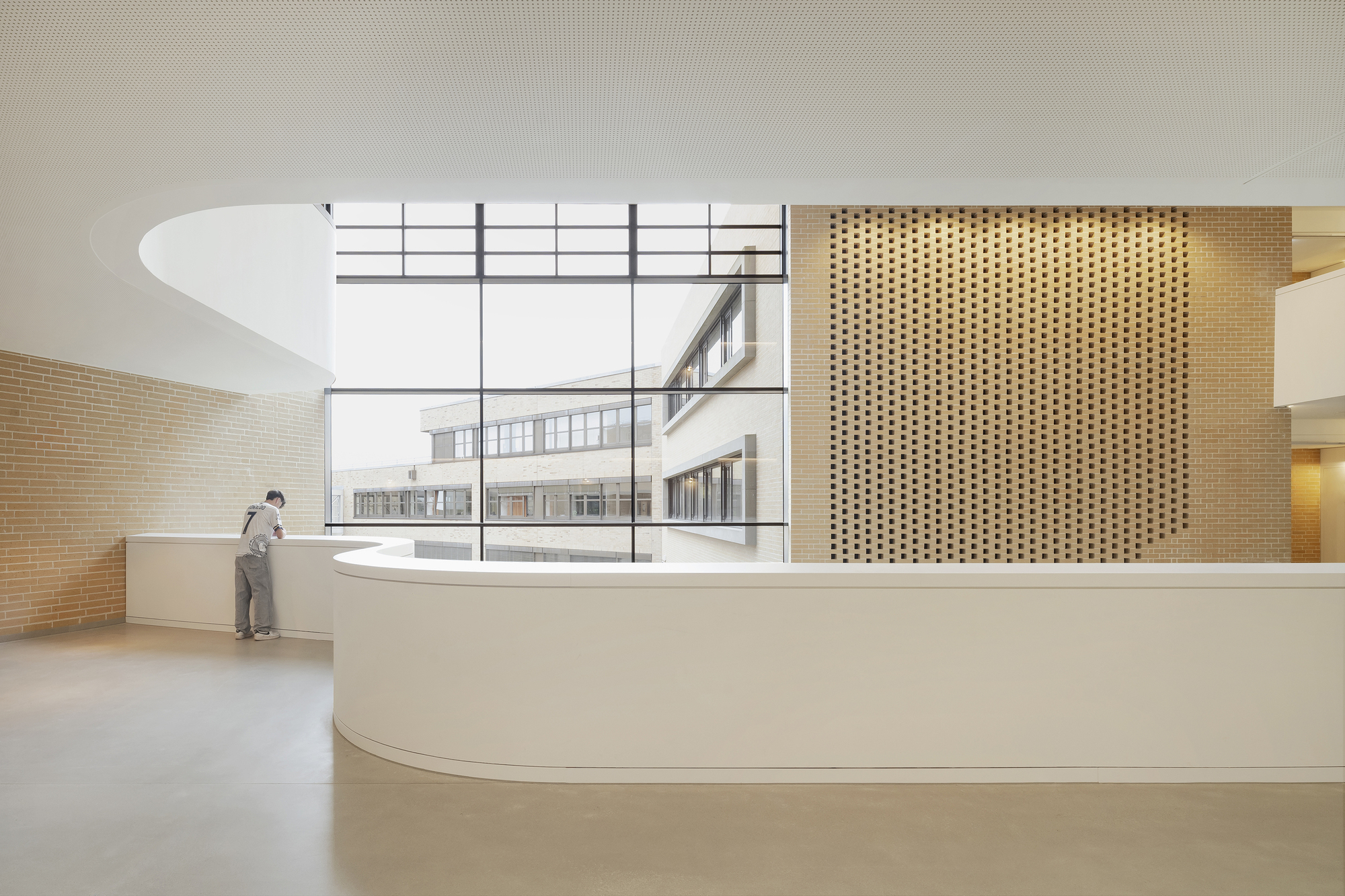 Curved reception counter with perforated wood screen and clerestory window overlooking an adjacent building