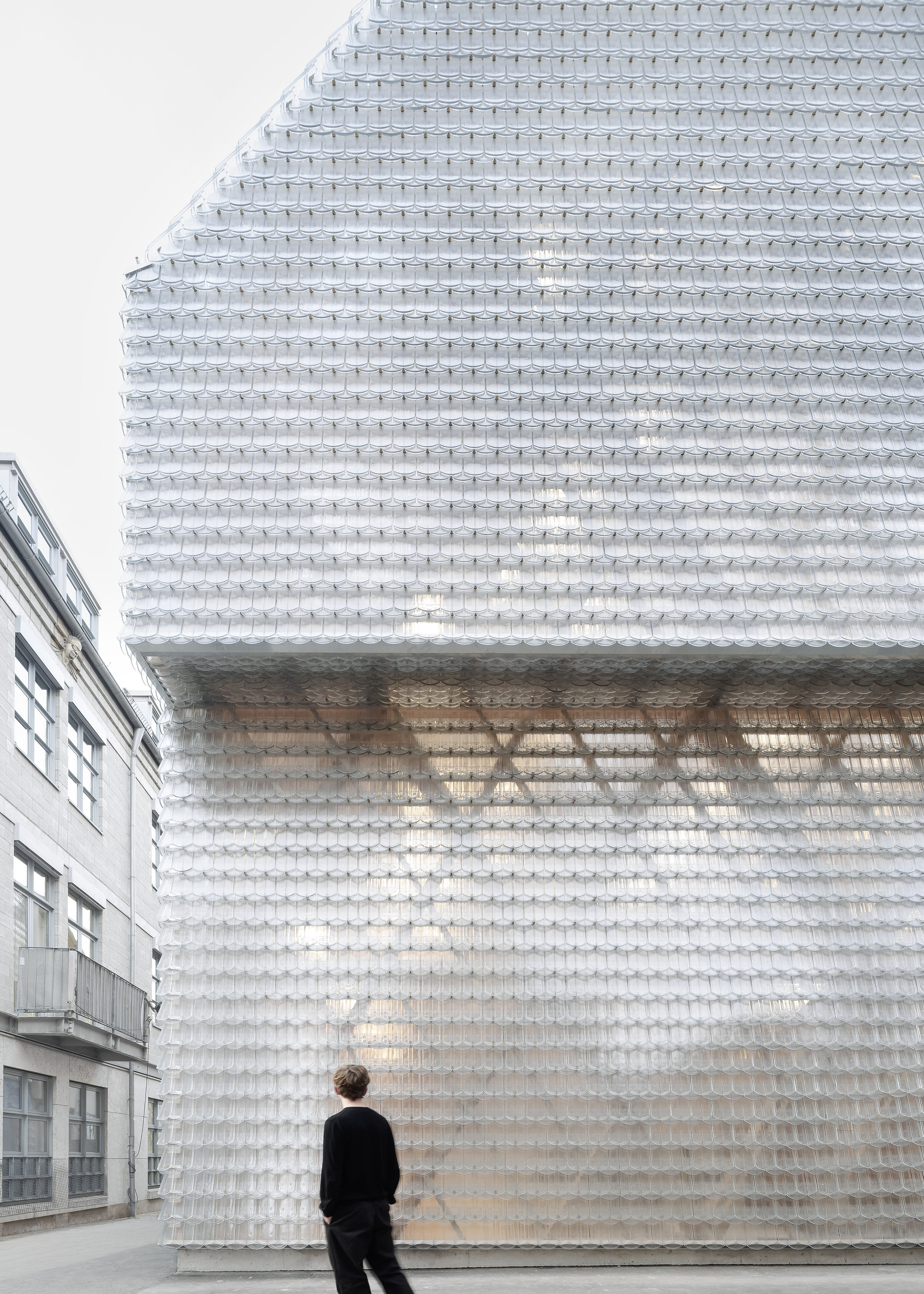 Translucent glass brick facade with recessed opening and a person standing at street level