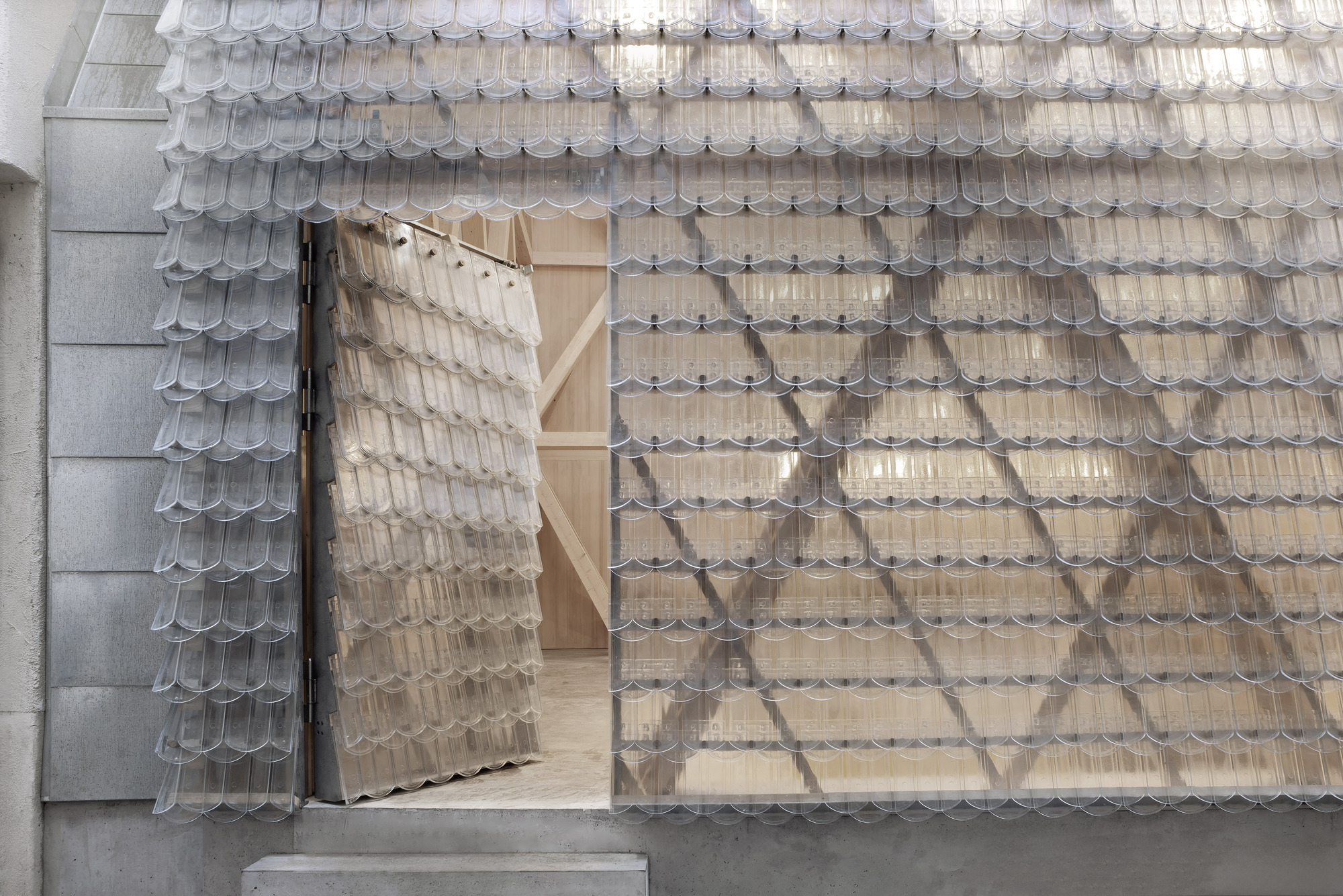 Aerial view of the shingled roof with an open pivoting door revealing the light timber interior