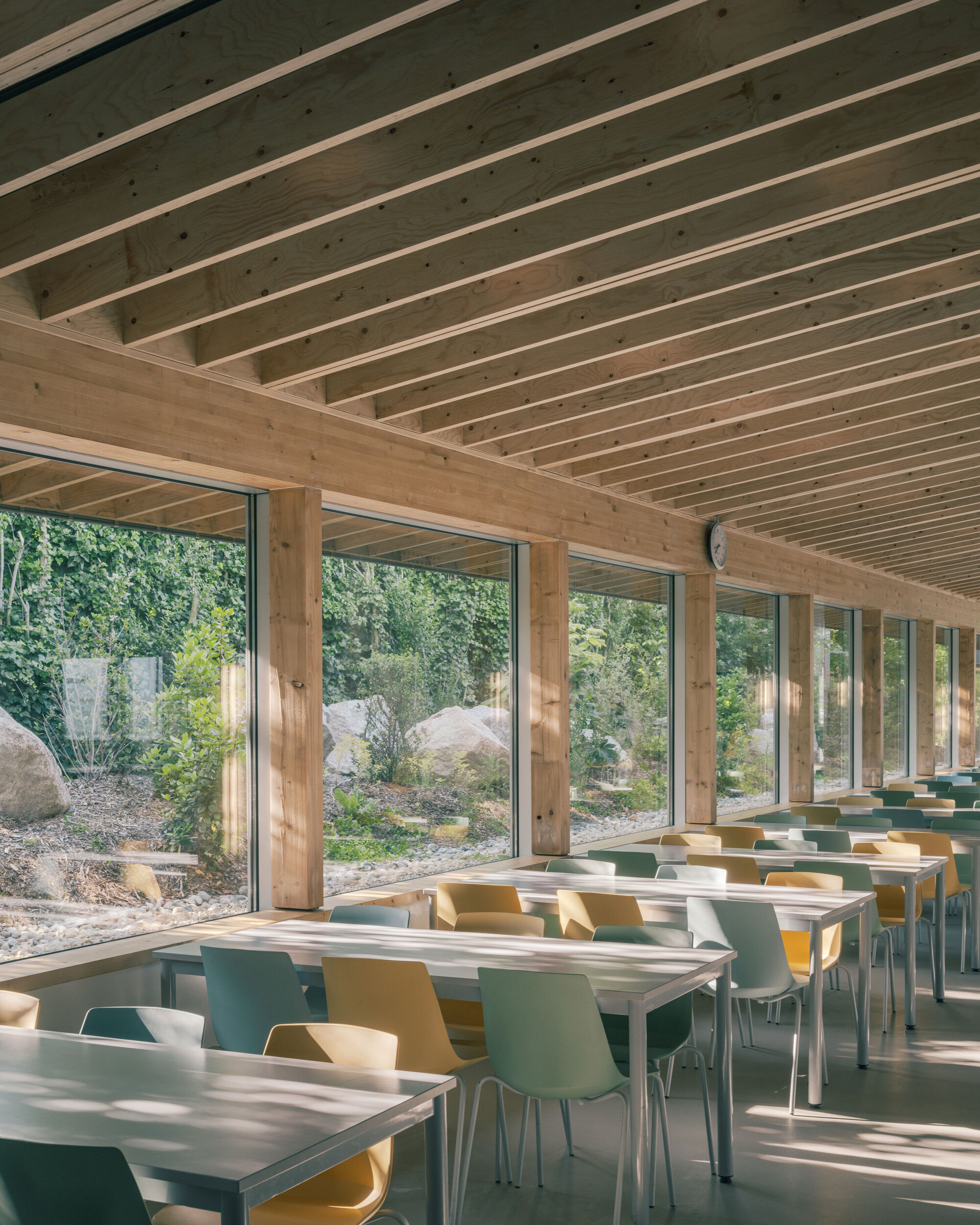 Timber frame posts and exposed ceiling beams above dining tables facing the landscaped courtyard