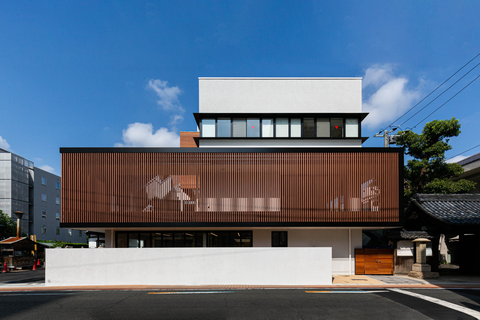 Street view of the layered facade with vertical timber screening on the middle level