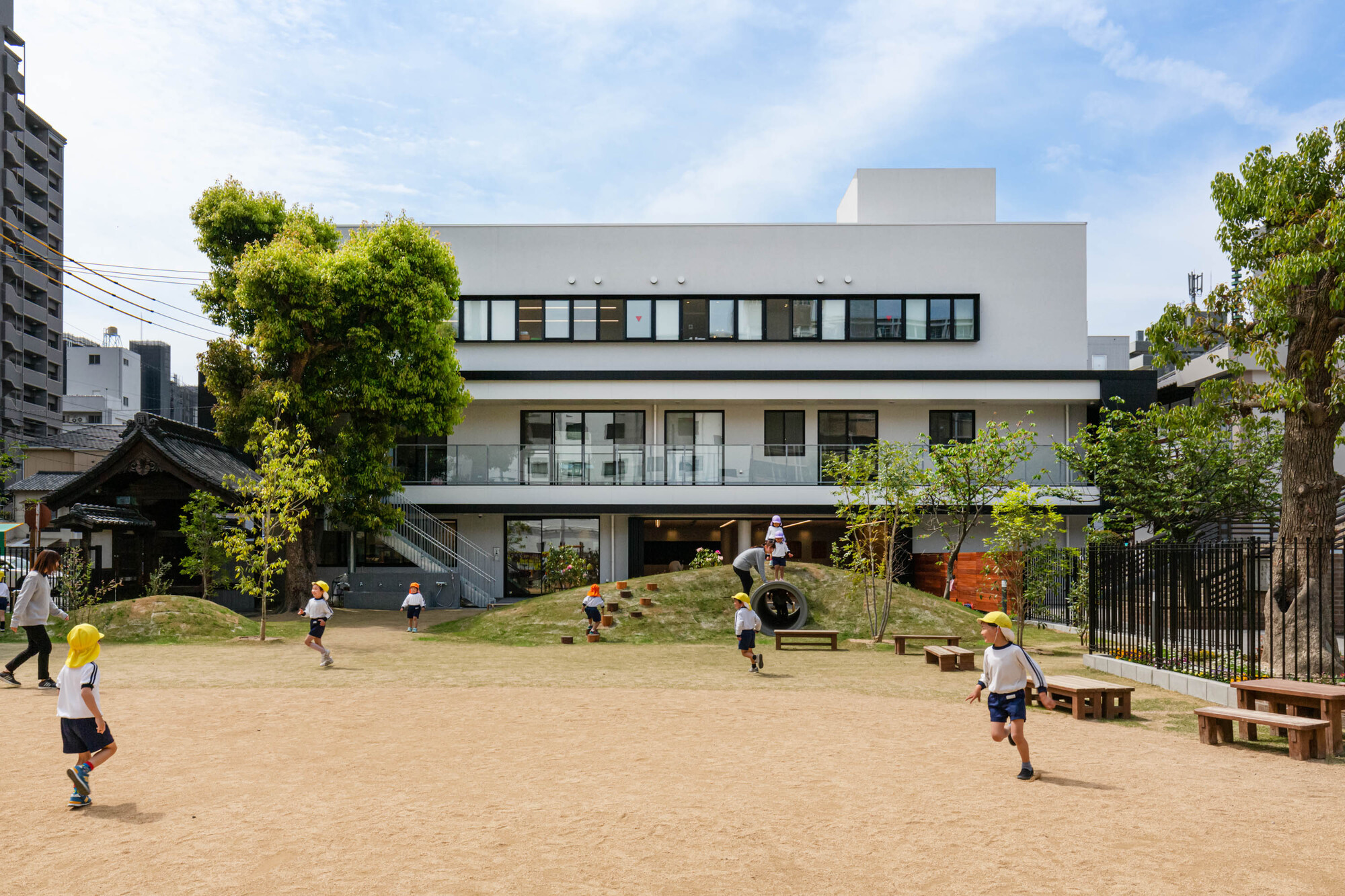 View from the playground with children at play beneath the raised white volume