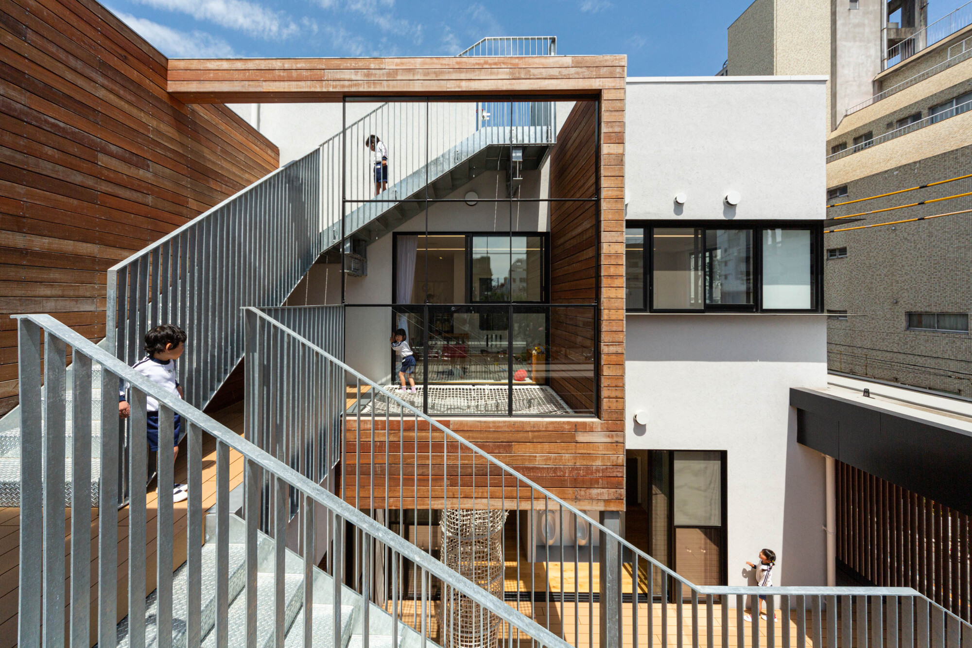 Exterior staircase with corrugated metal screen connecting multiple levels with children walking