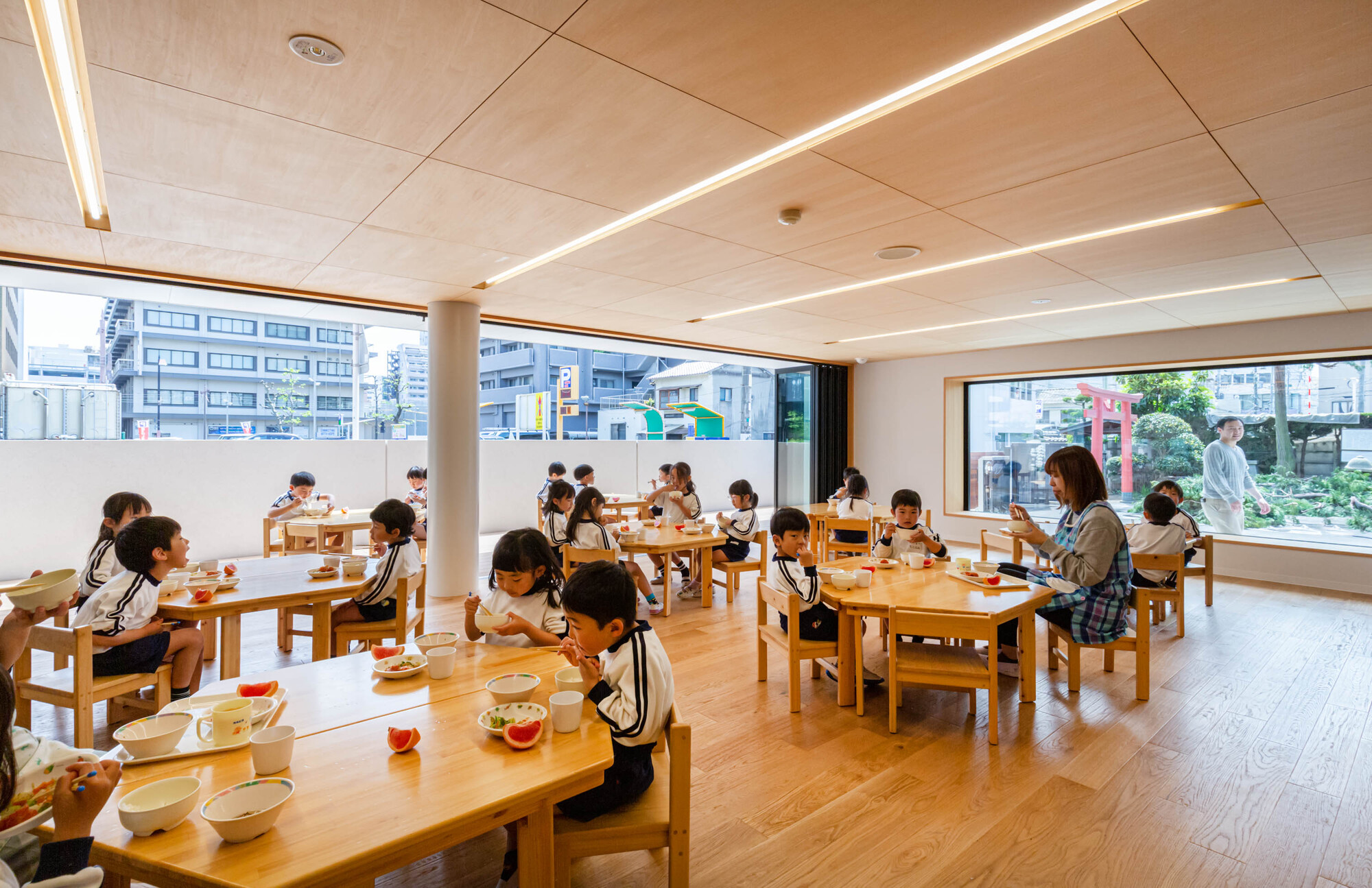 Dining room with timber tables, ceiling-mounted linear lighting and corner windows overlooking the street