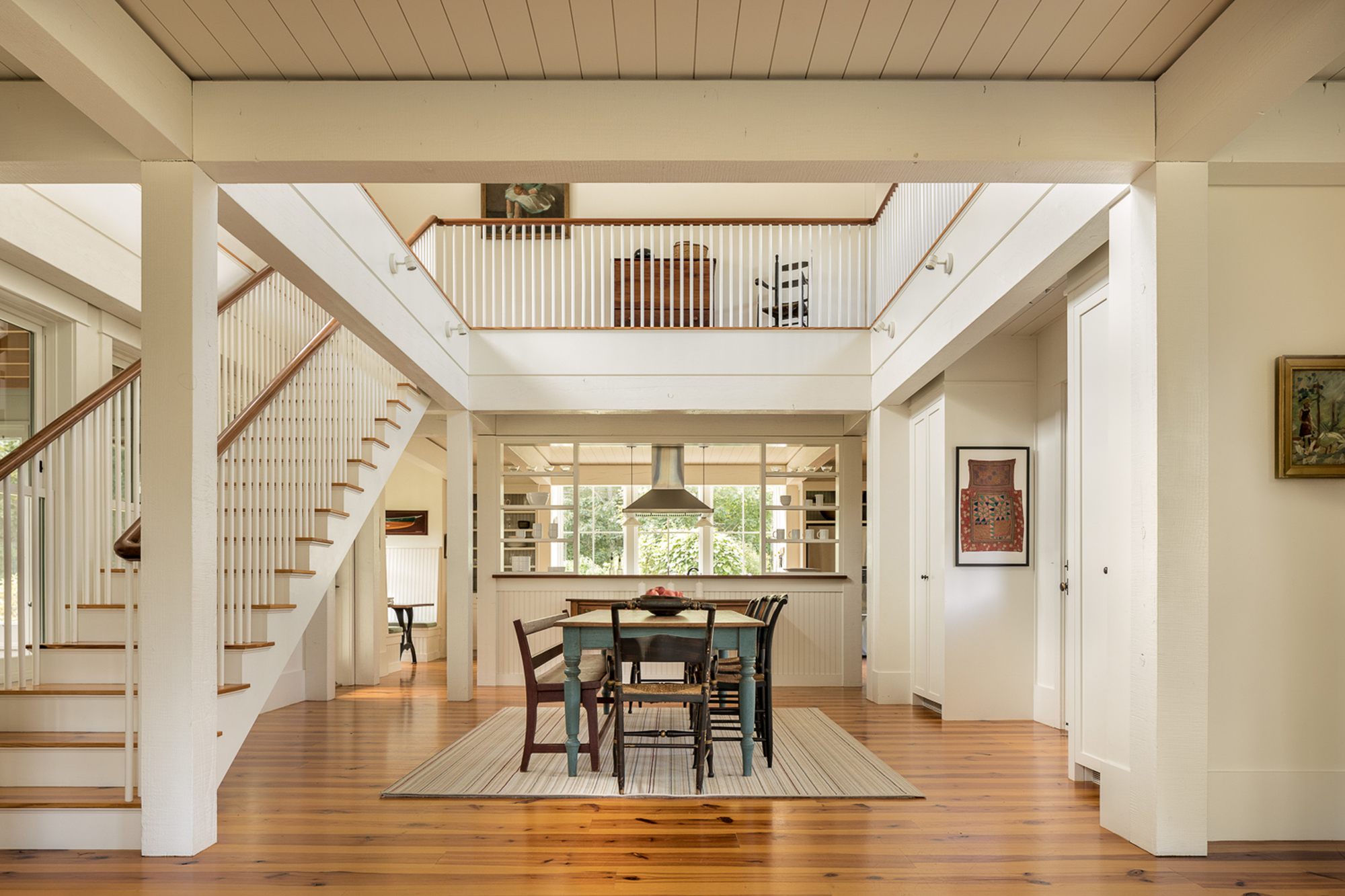 Double-height dining space with wood floors, open stair and mezzanine overlooking the kitchen