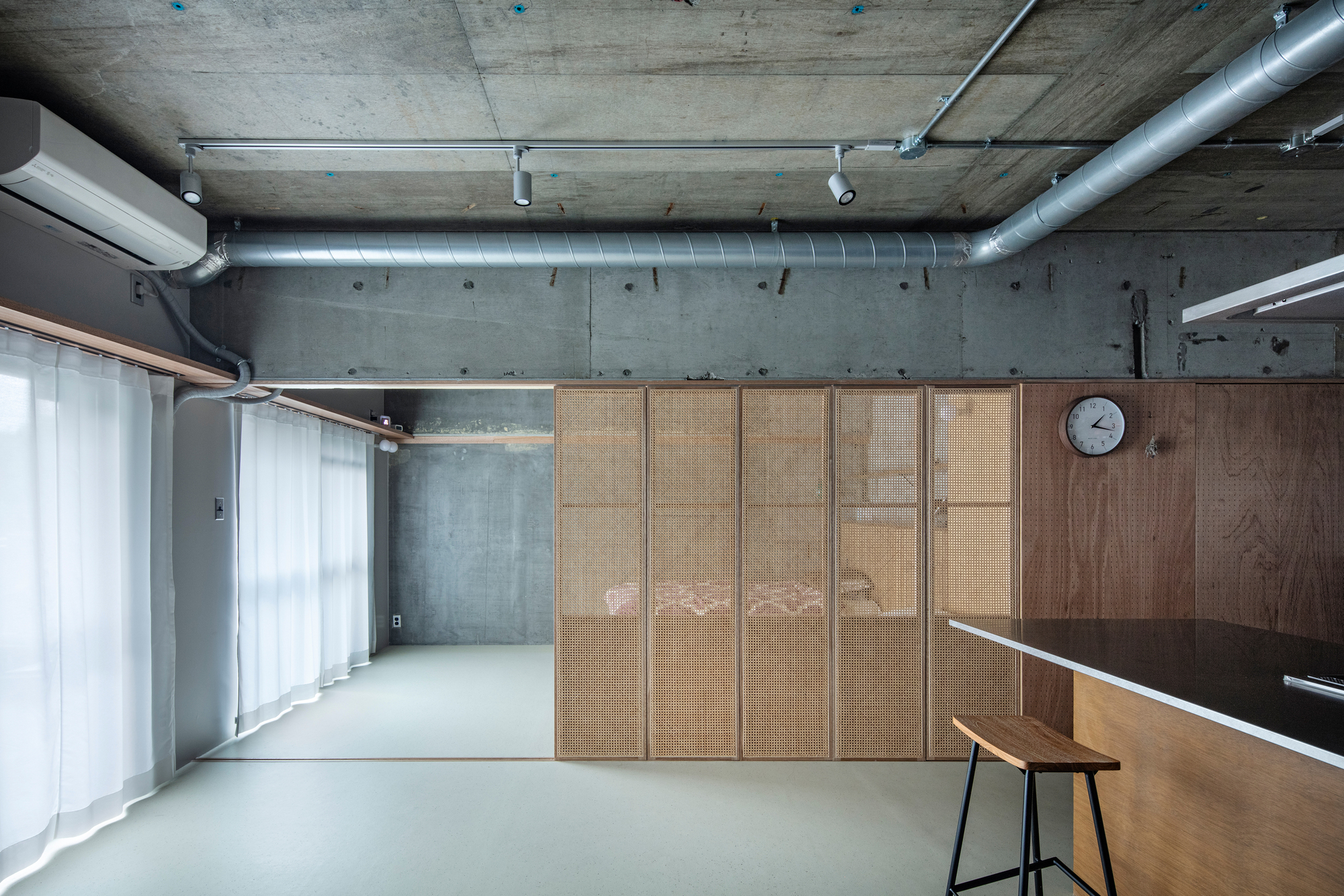 Sliding partition system with woven cane inserts closed to conceal the sleeping area behind the main space