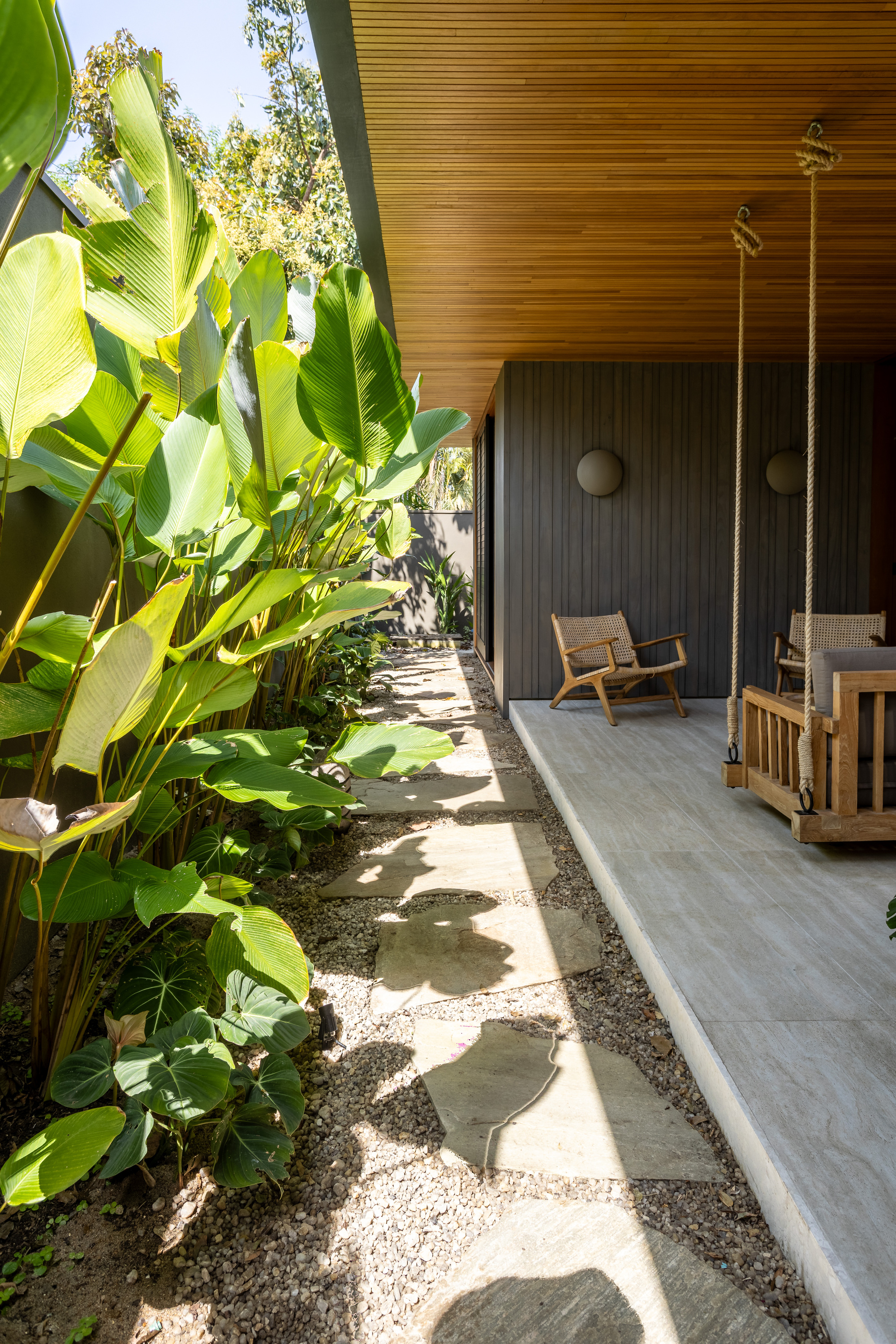 Narrow garden pathway with stepping stones and banana plants alongside the timber-clad wall