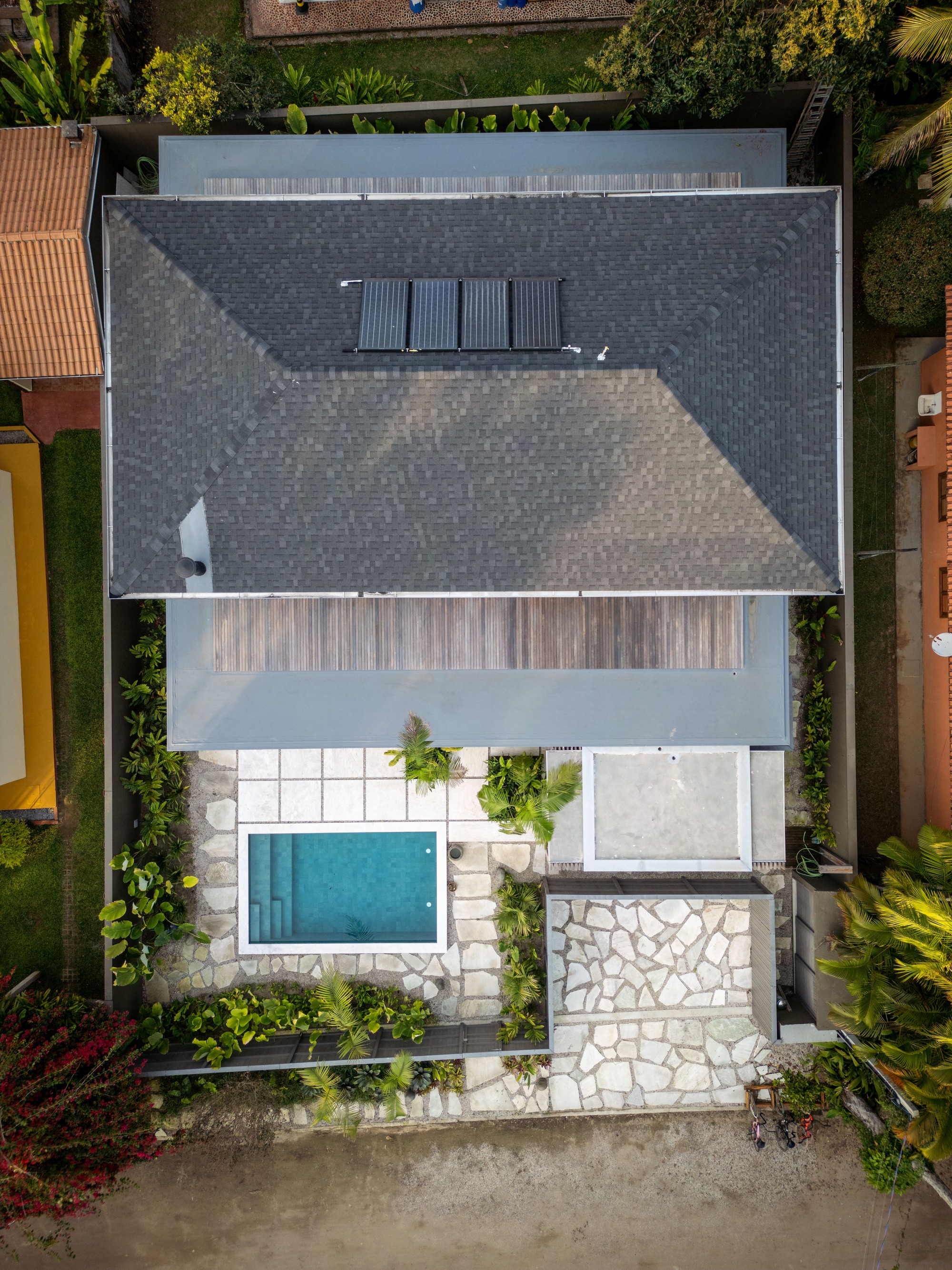Aerial view of the dark tiled roof with solar panels and the pool courtyard below