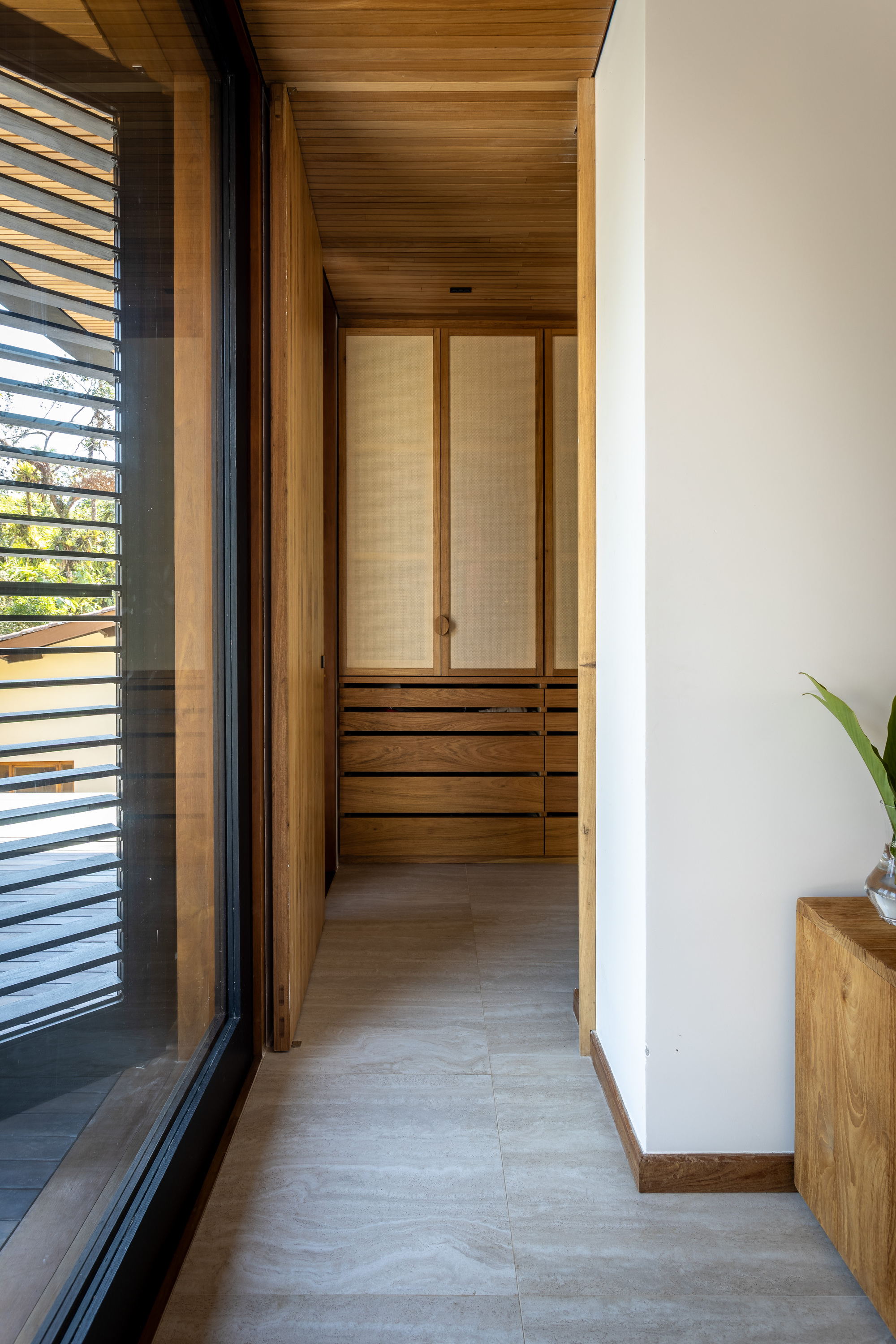 Narrow corridor with timber ceiling and built-in wardrobe with louvered sliding doors at the end
