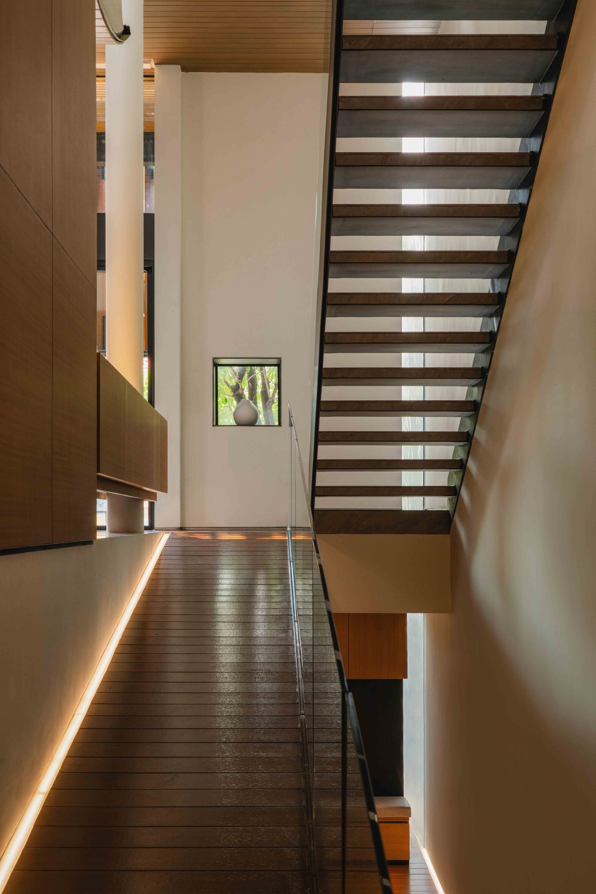 Open timber tread staircase with glass balustrade and suspended wood millwork alongside the landing