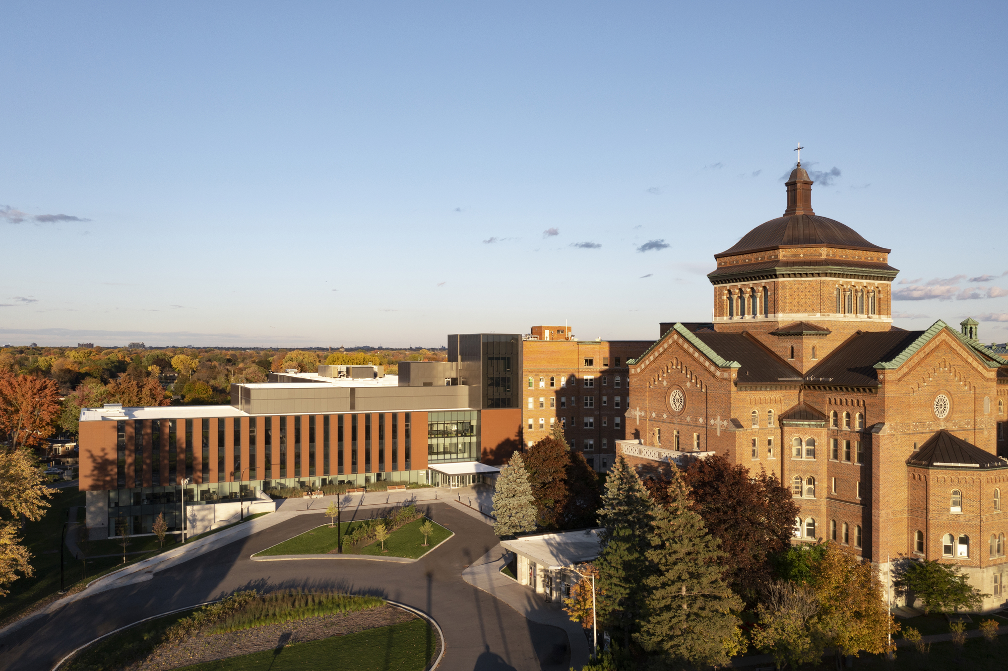 Aerial view of the campus complex with historic brick buildings and new volumes in autumn light
