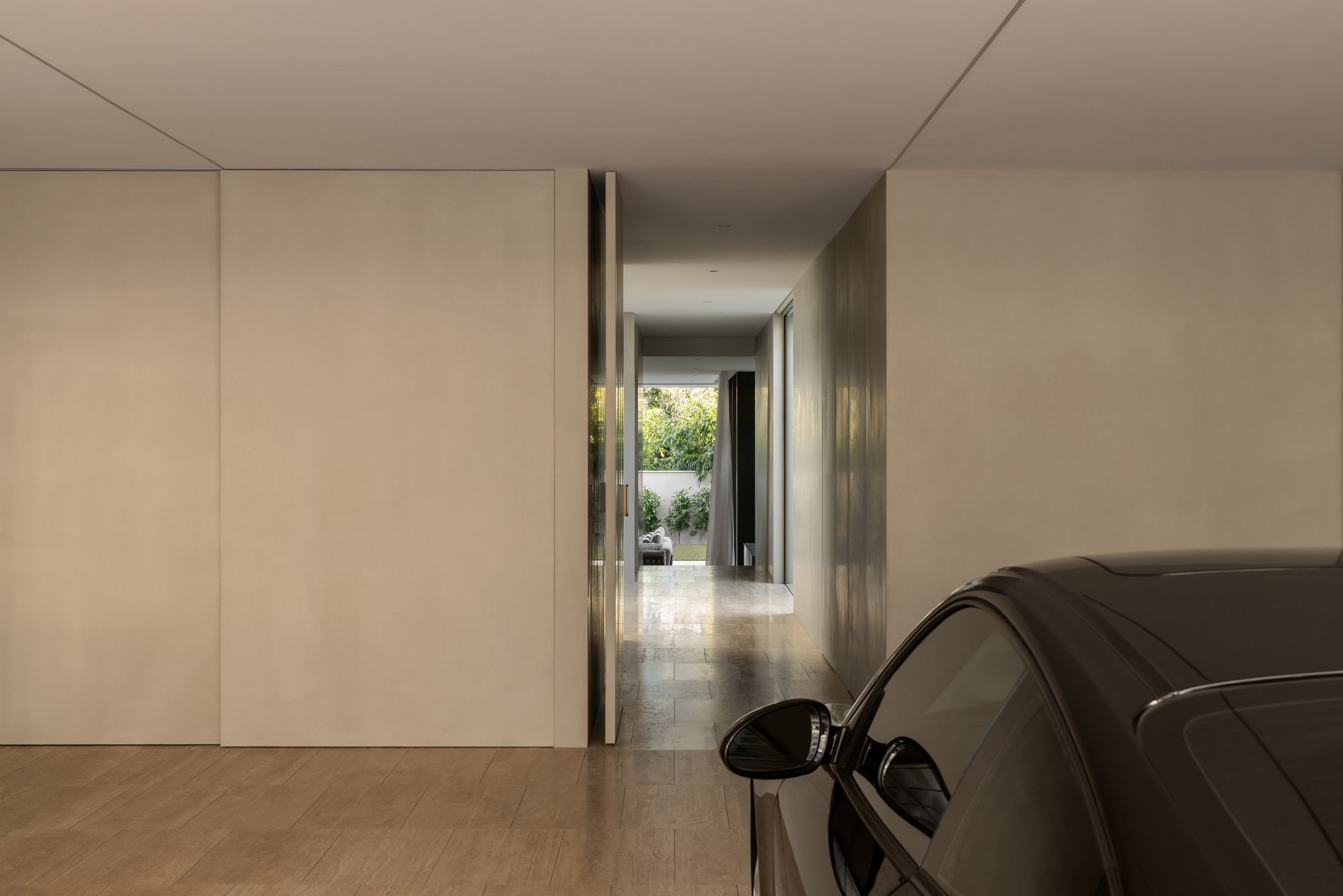 Pale timber-floored garage with flush wall panels and a view through to a sunlit courtyard
