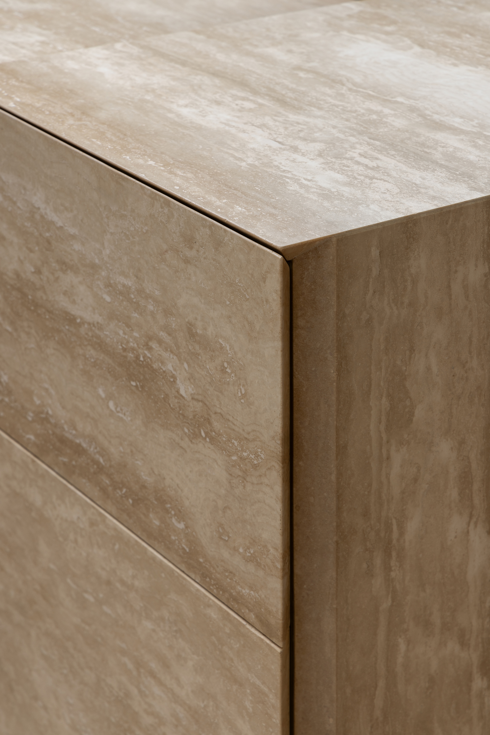 Close-up of a beige travertine corner edge with flush shadow joints