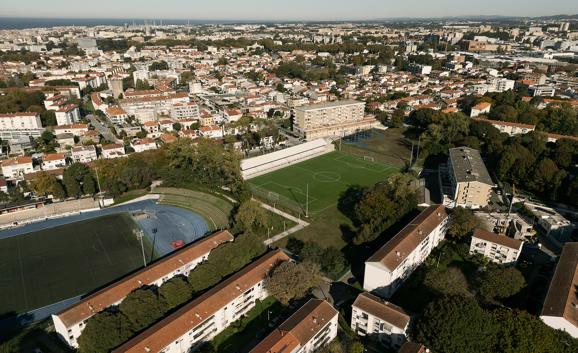 Aerial view of a long linear sports pavilion beside playing fields and residential buildings