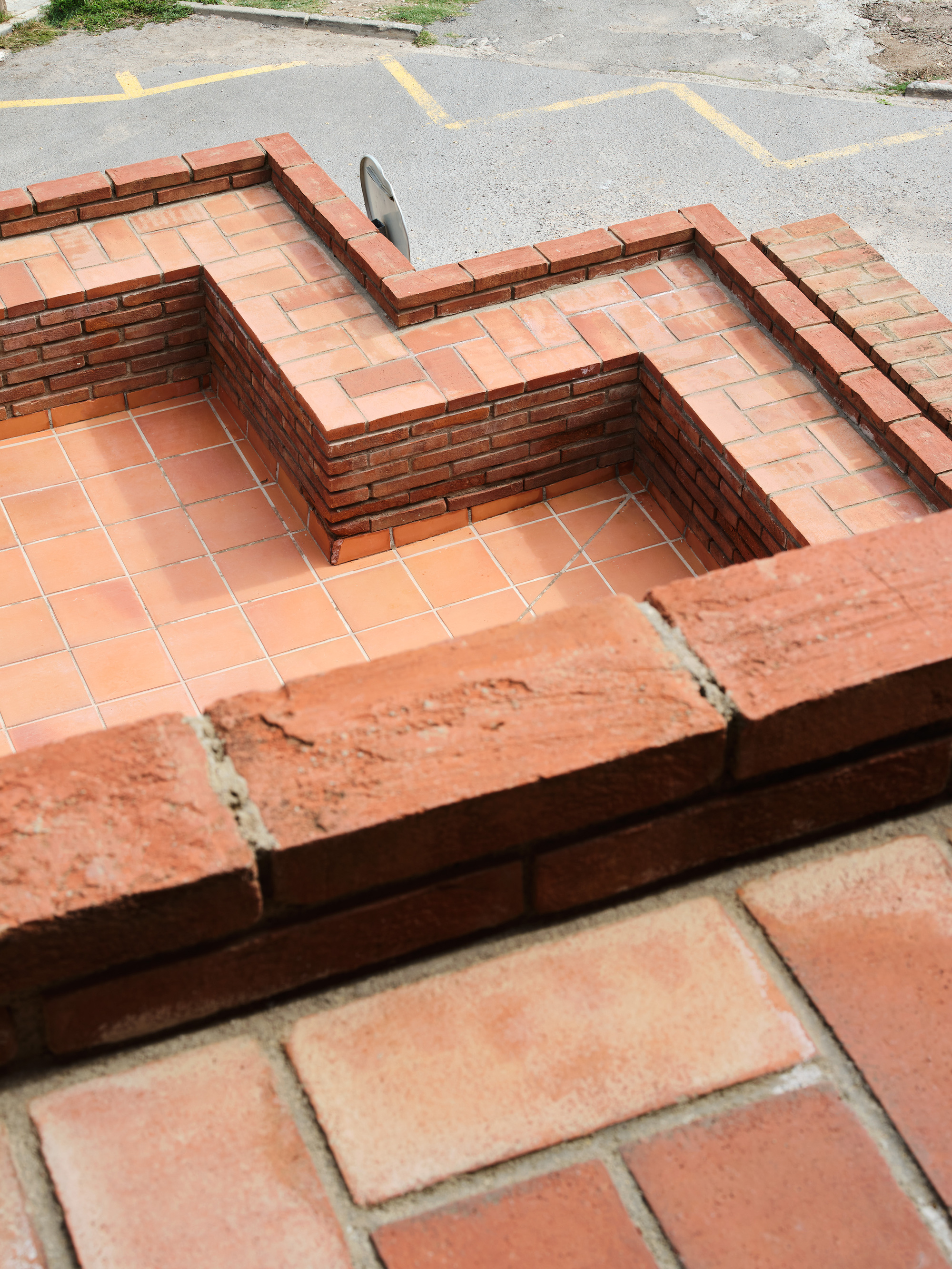 Close-up of stepped brick and terracotta tile detail at roof level with street pavement visible