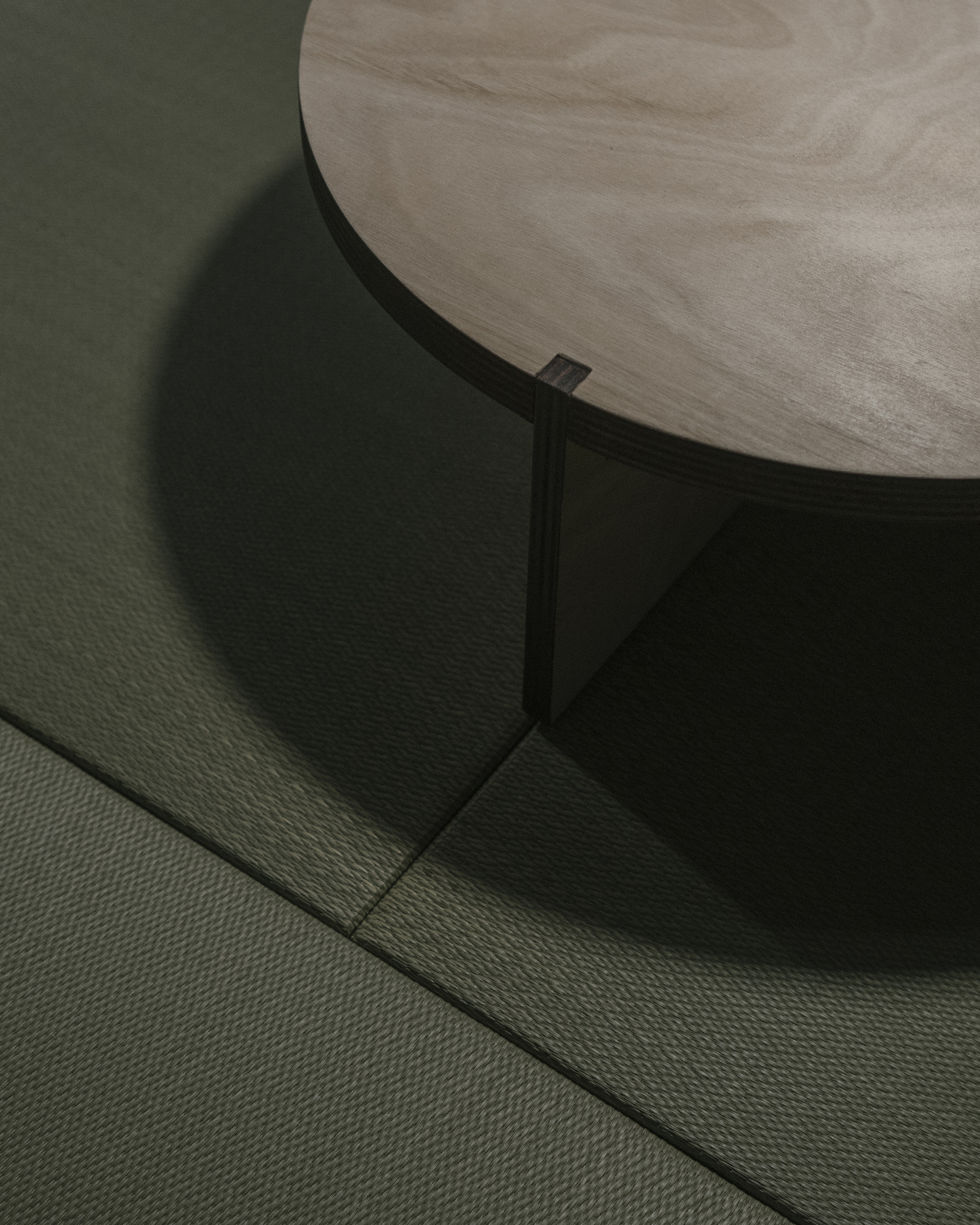 Circular stone tabletop with black steel base casting shadows on textured flooring