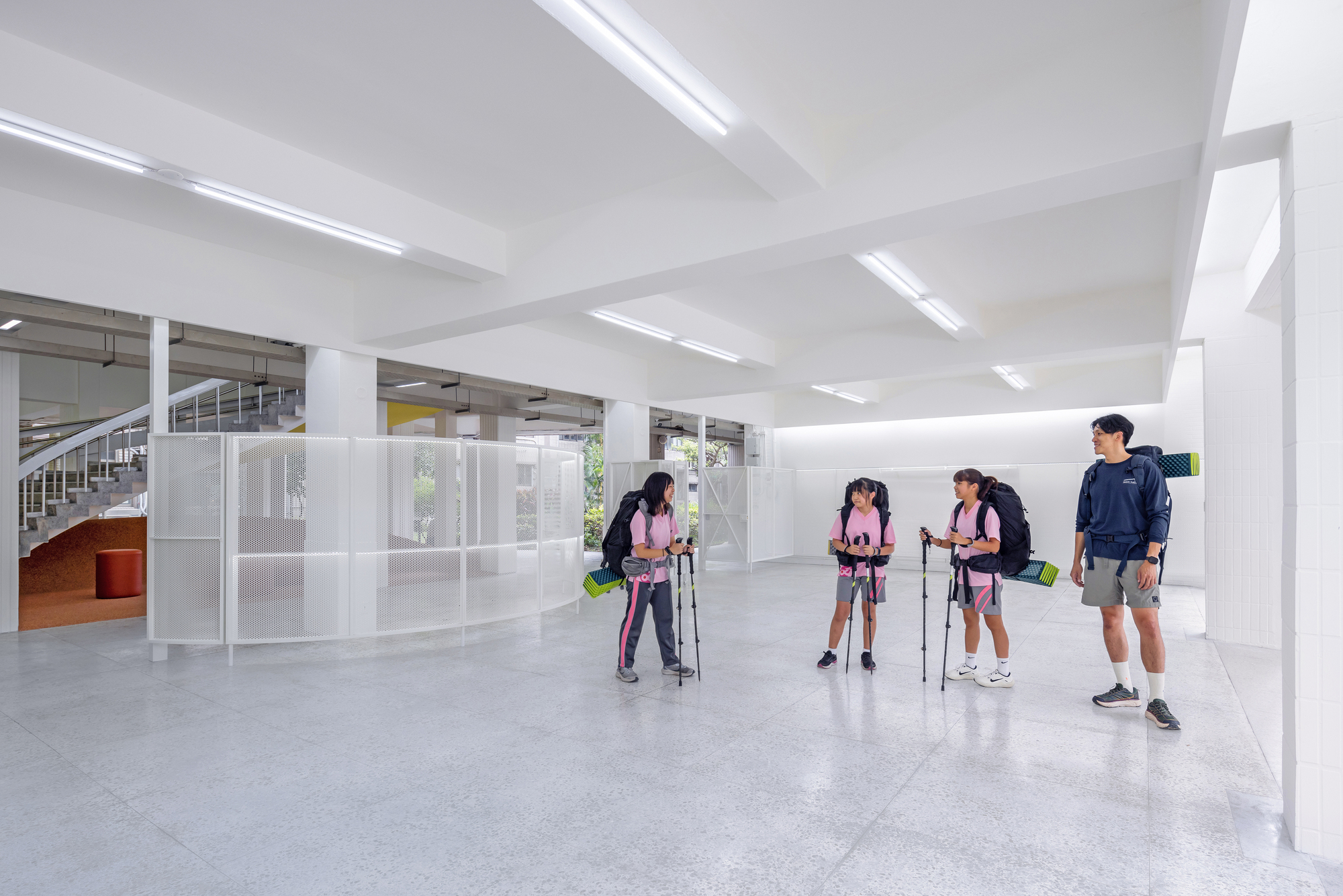 Entry space with exposed concrete ceiling beams and students preparing hiking gear on the floor