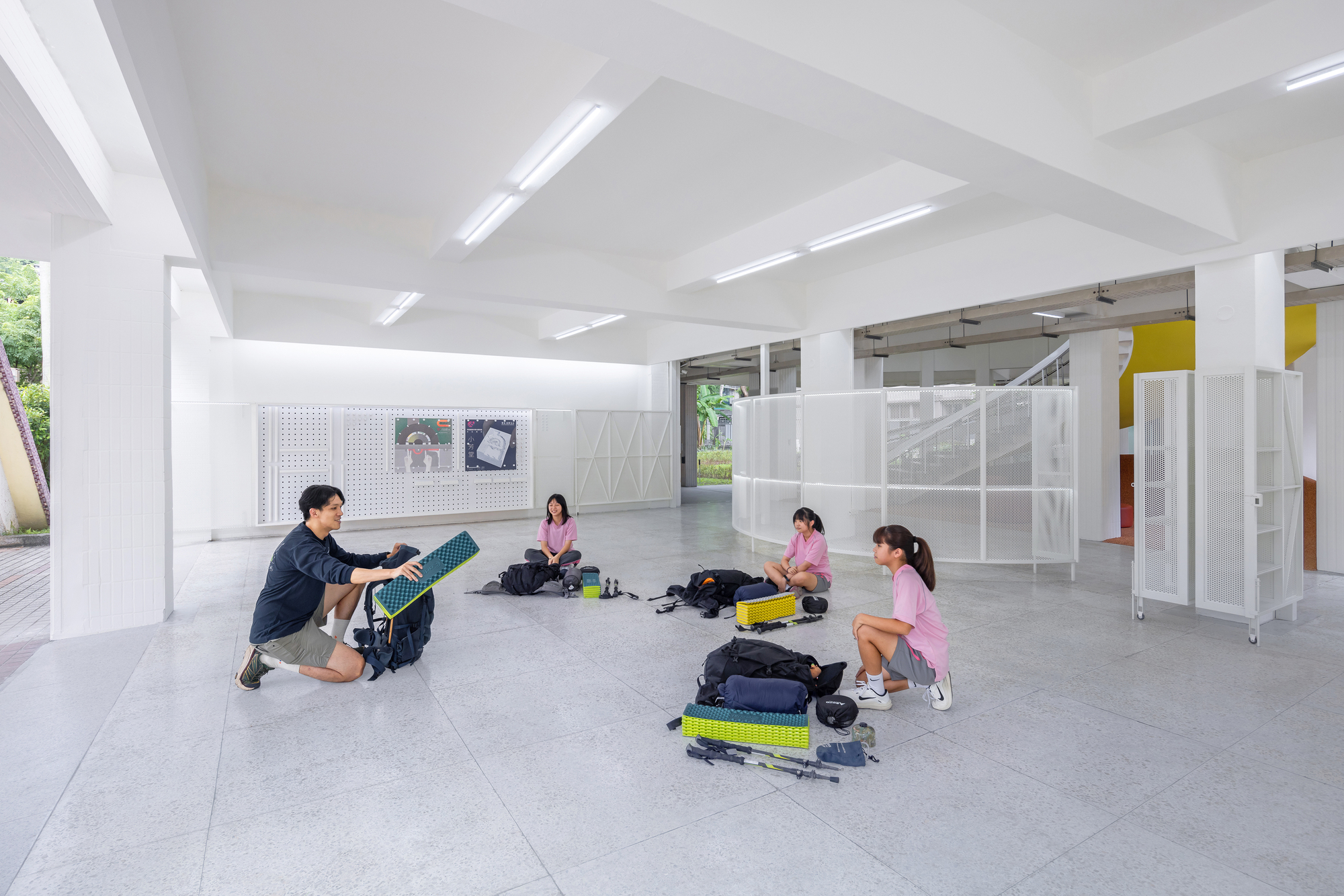Group sitting on terrazzo flooring organizing backpacks beneath linear fluorescent lighting fixtures