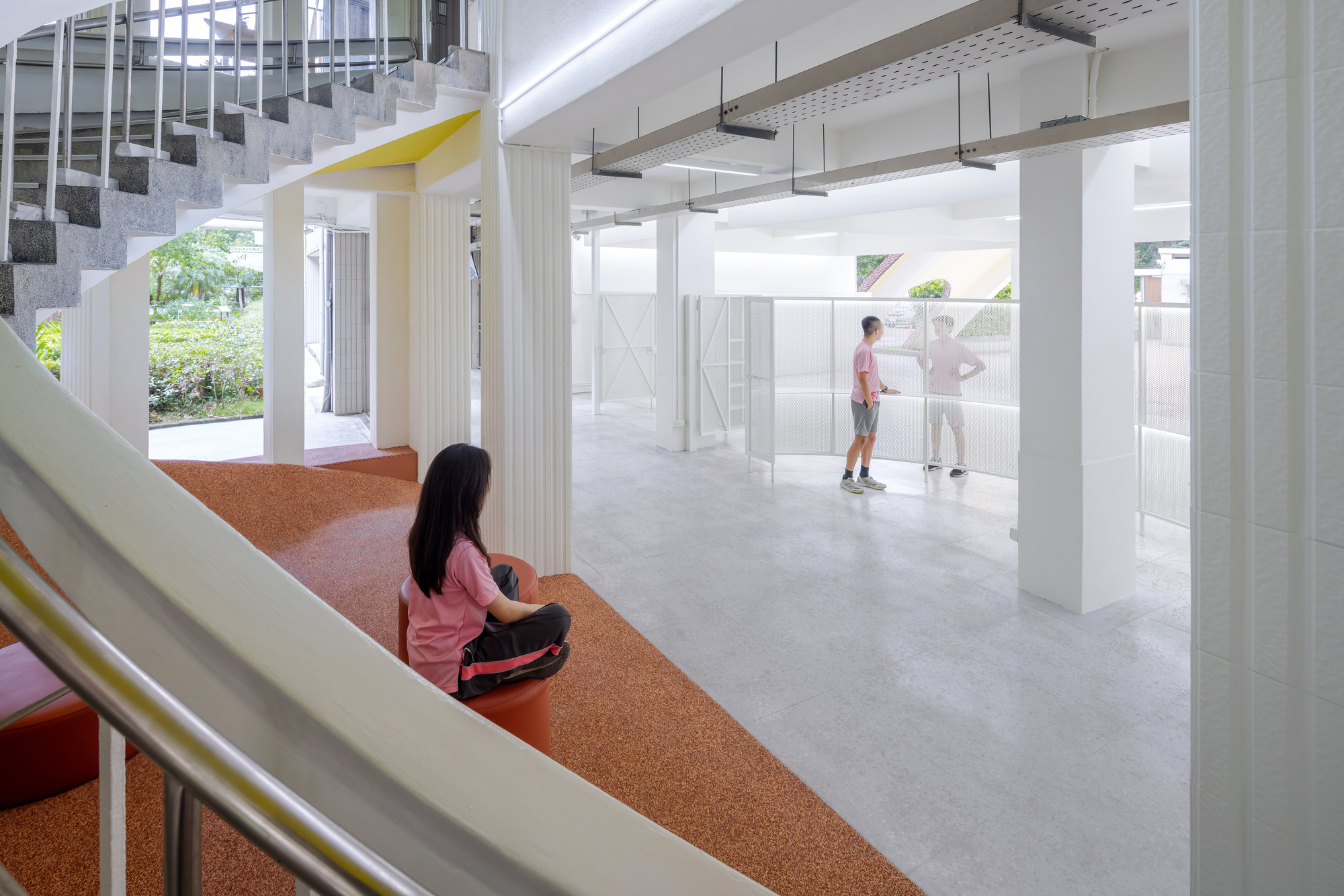 View from orange rubber staircase landing toward white columns and movable partitions below