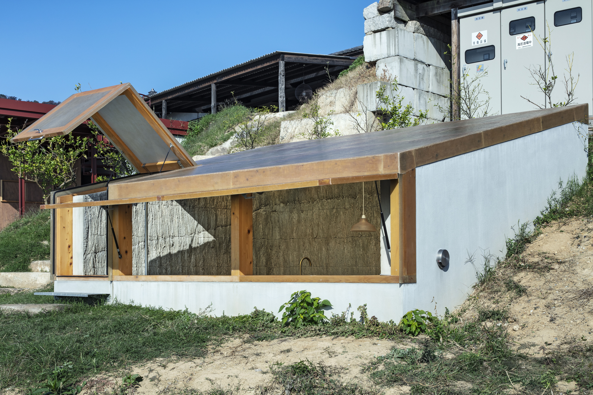 Close-up of timber frame structure with board-formed concrete wall and white stucco base