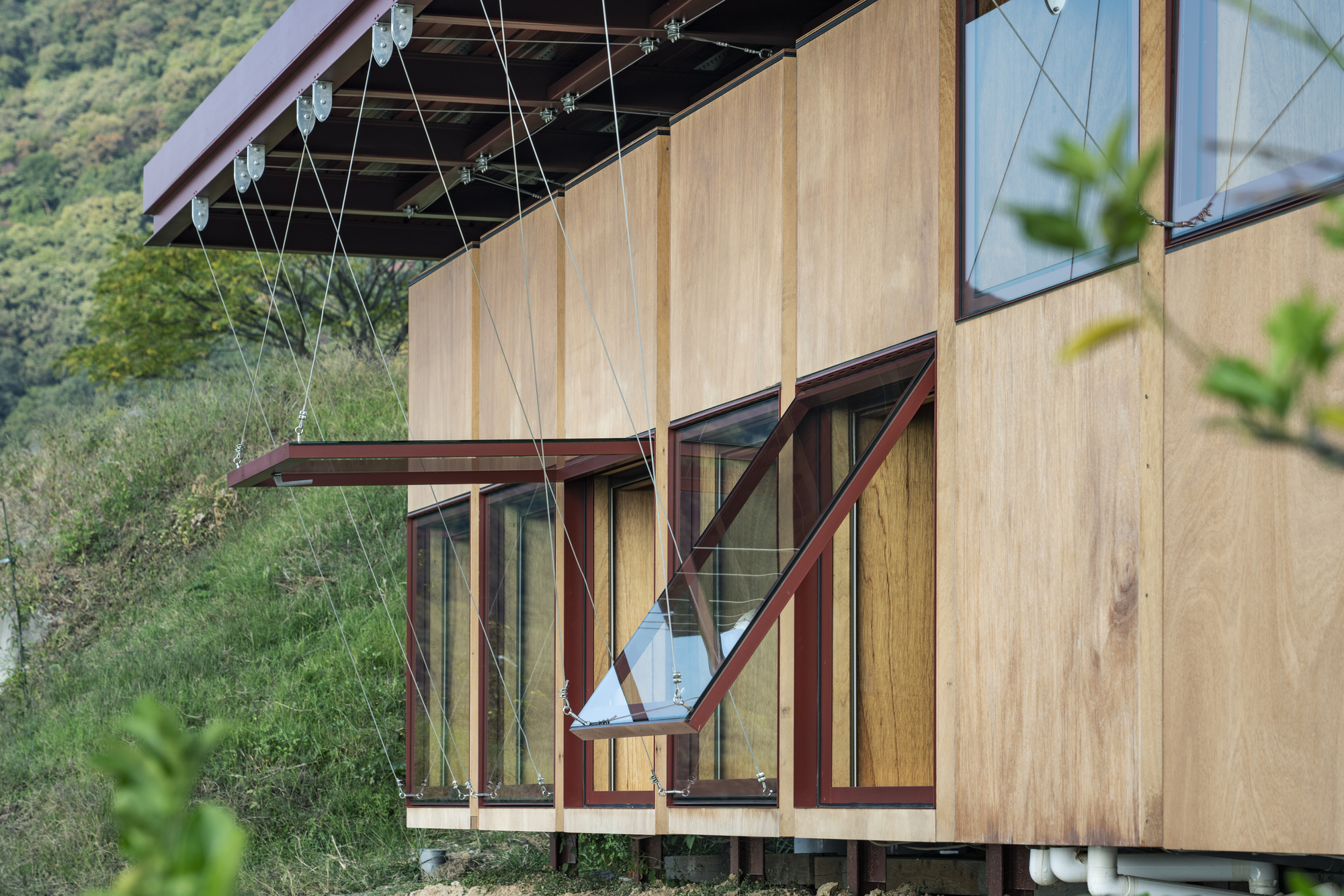 Close-up of the timber facade with operable window panels and cable bracing