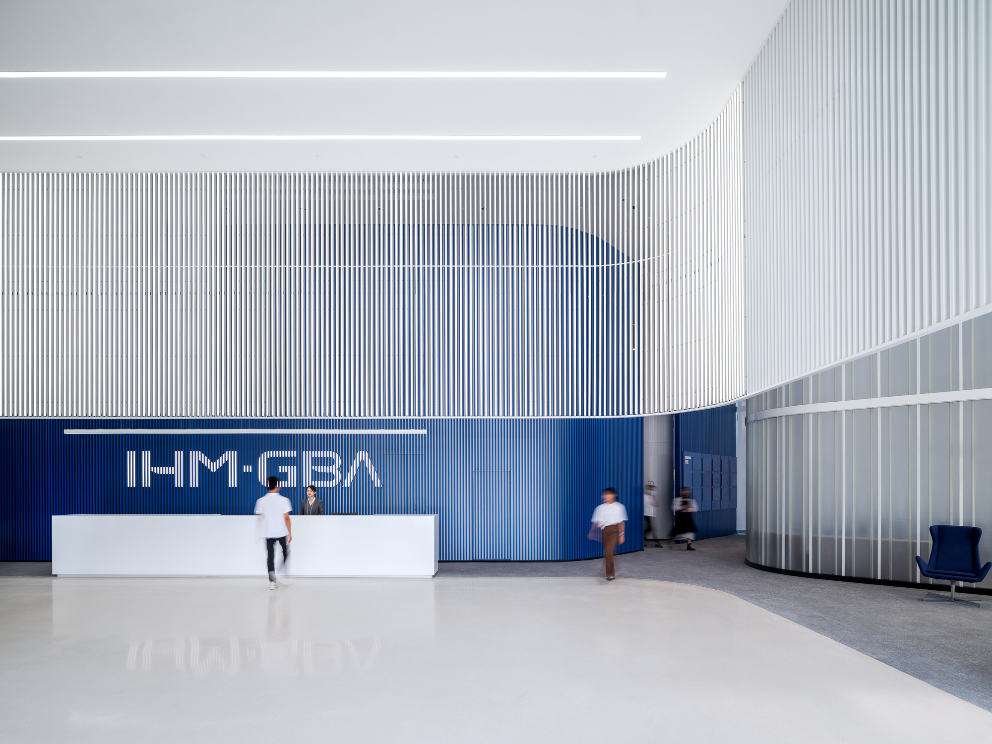 Reception area with white corrugated walls, a blue accent wall and people in motion